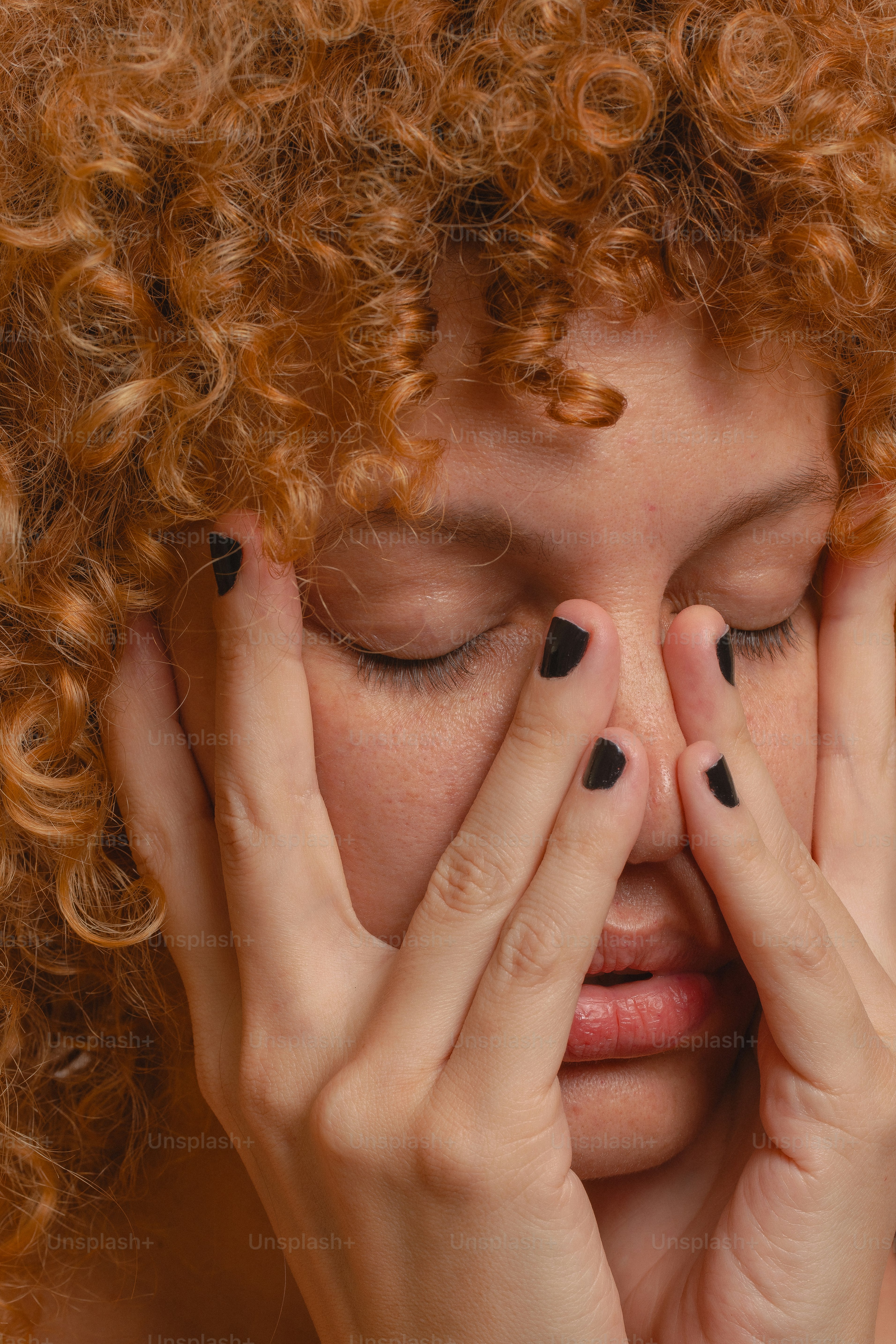 A woman covers her face with her hands.