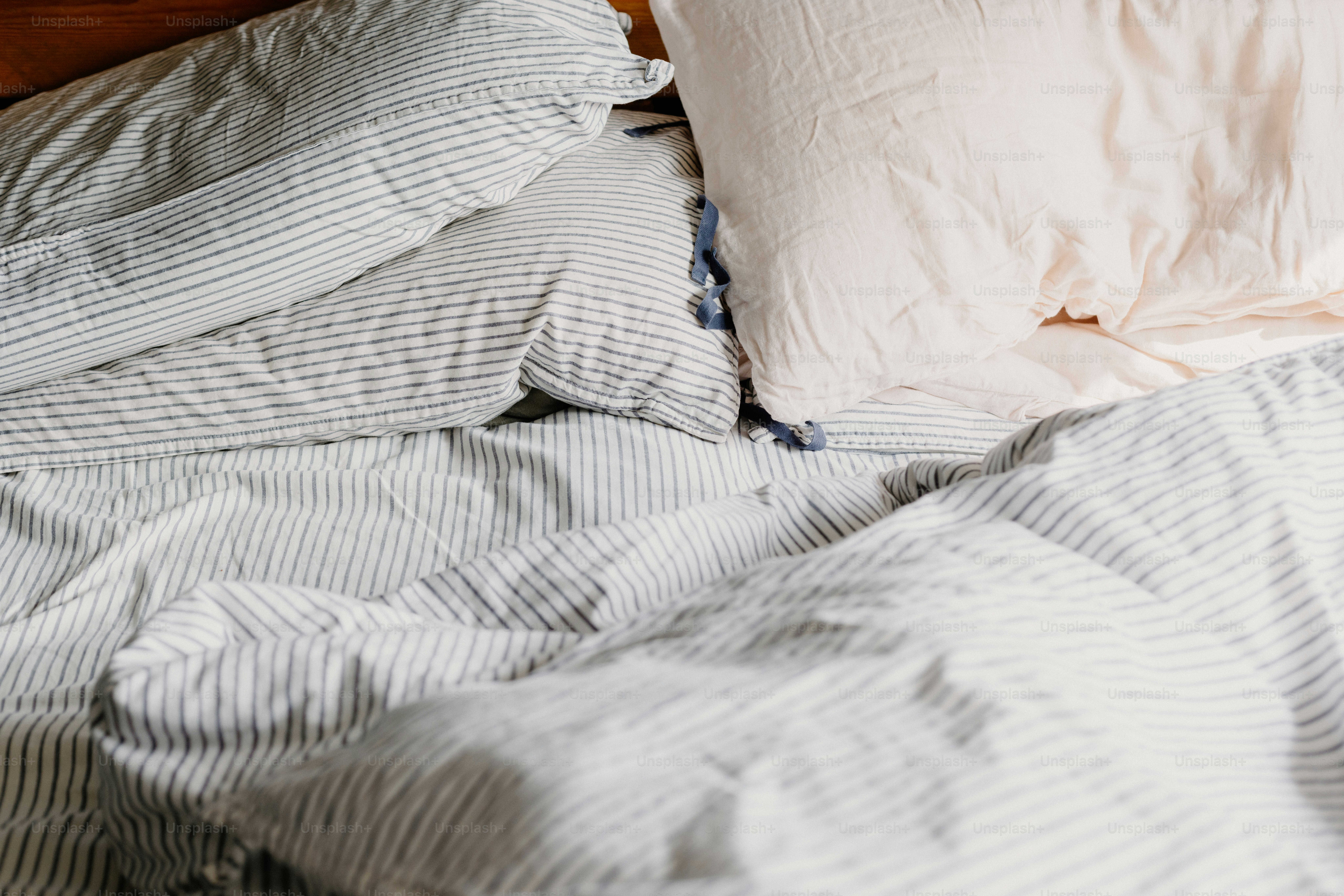 Ungemachtes Bett mit Kissen und gestreiften Laken