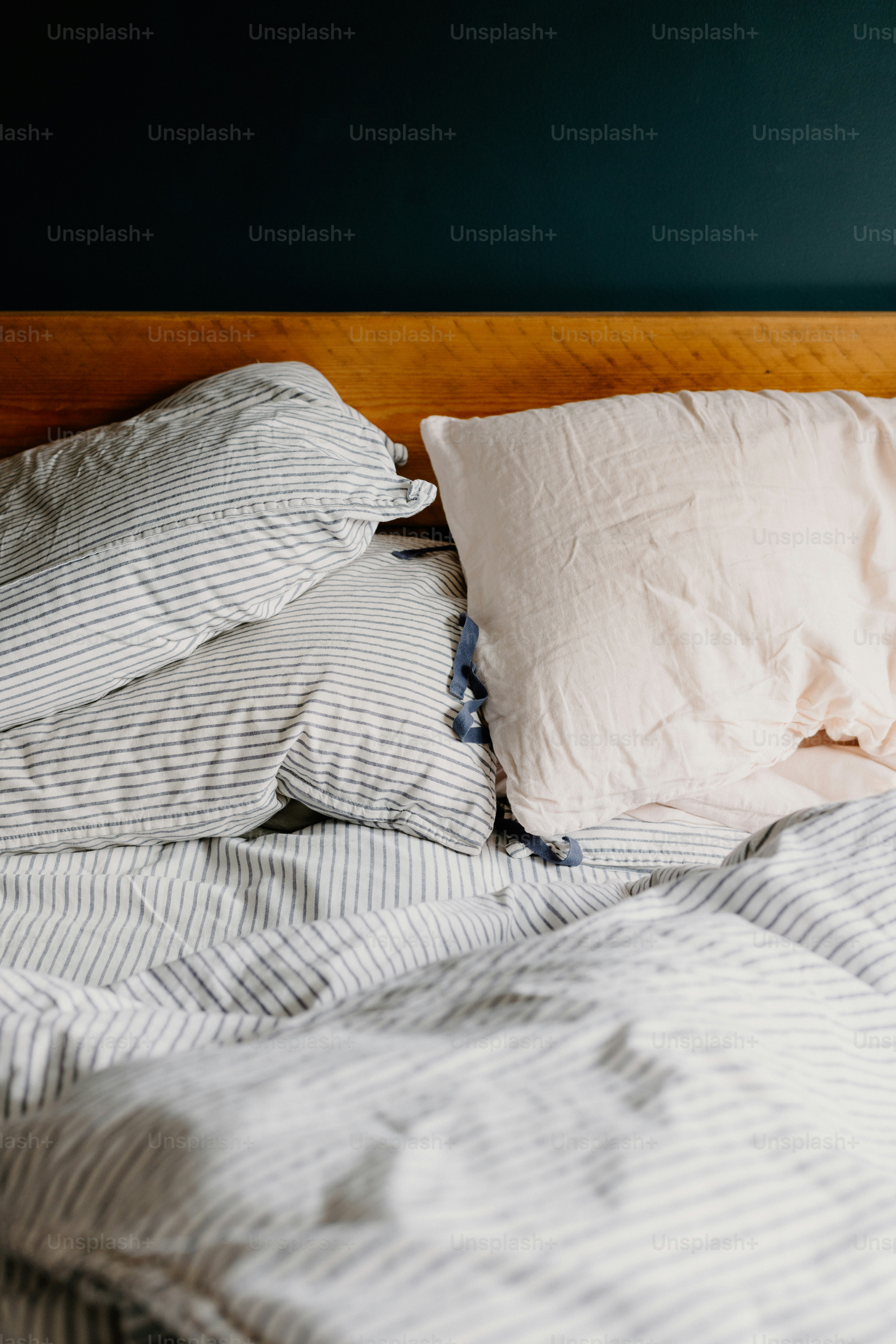 Bett mit Kissen und gestreifter Bettwäsche