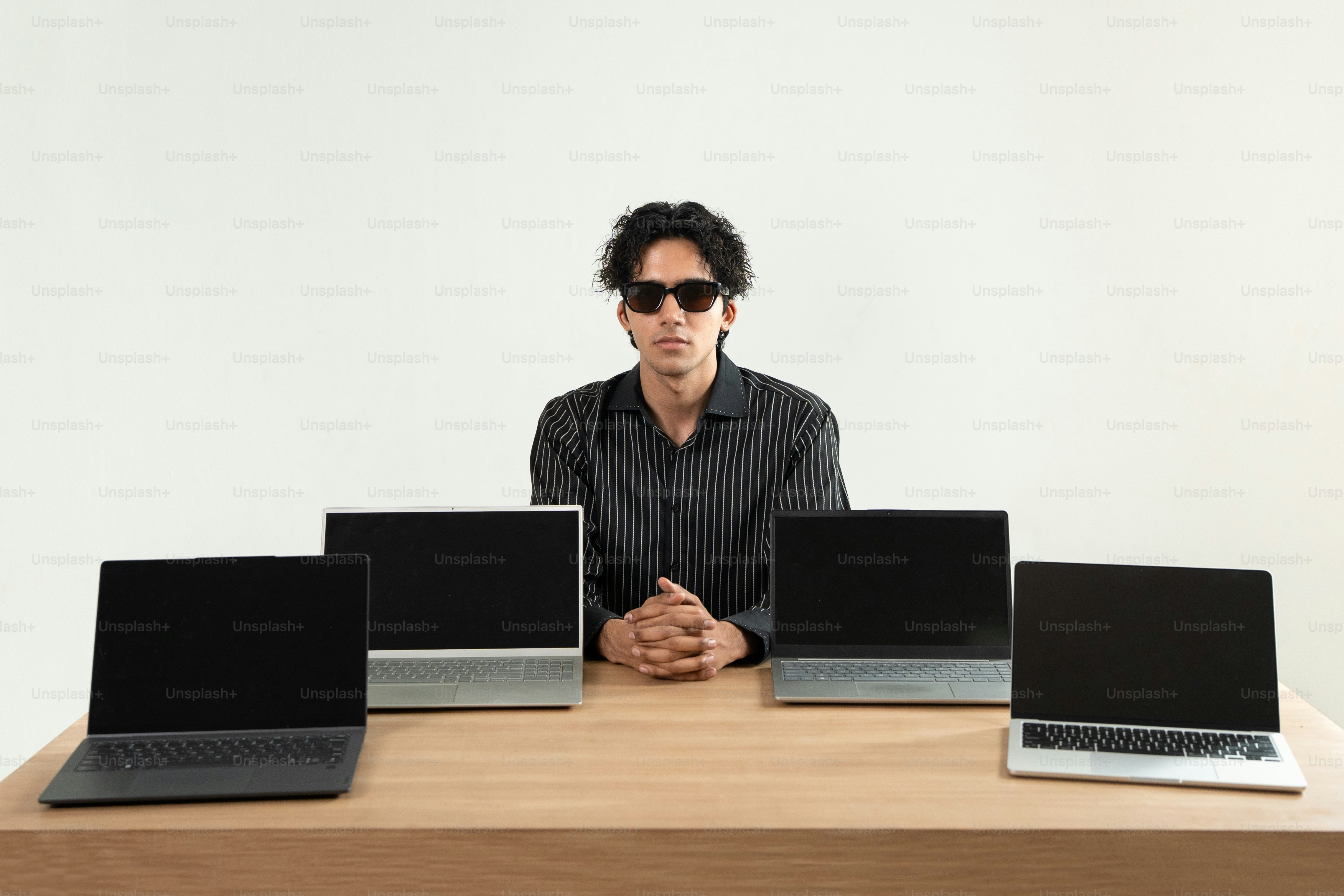 A man poses with several laptops. photo – Technology Image on Unsplash