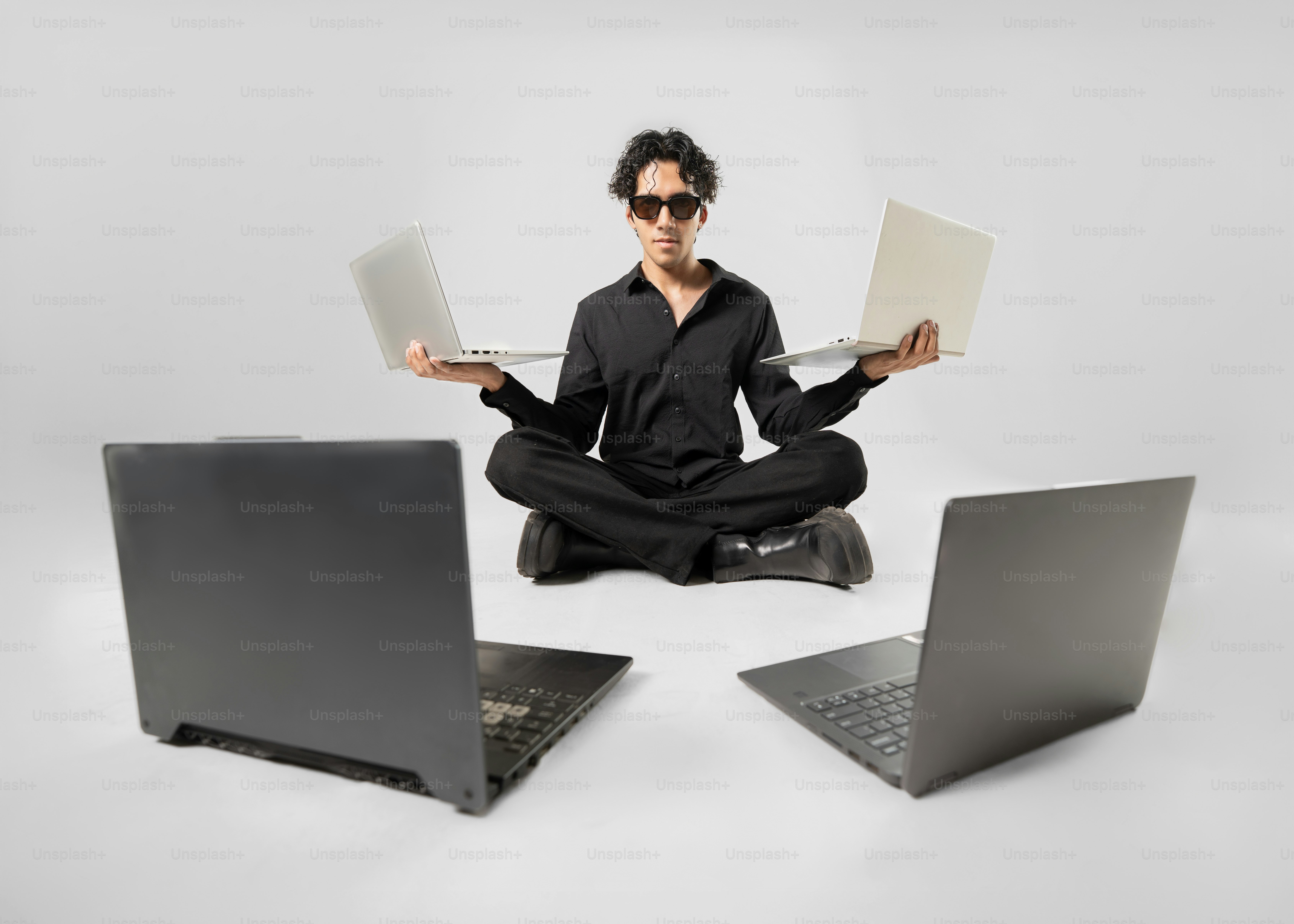 A man meditates with several laptops.