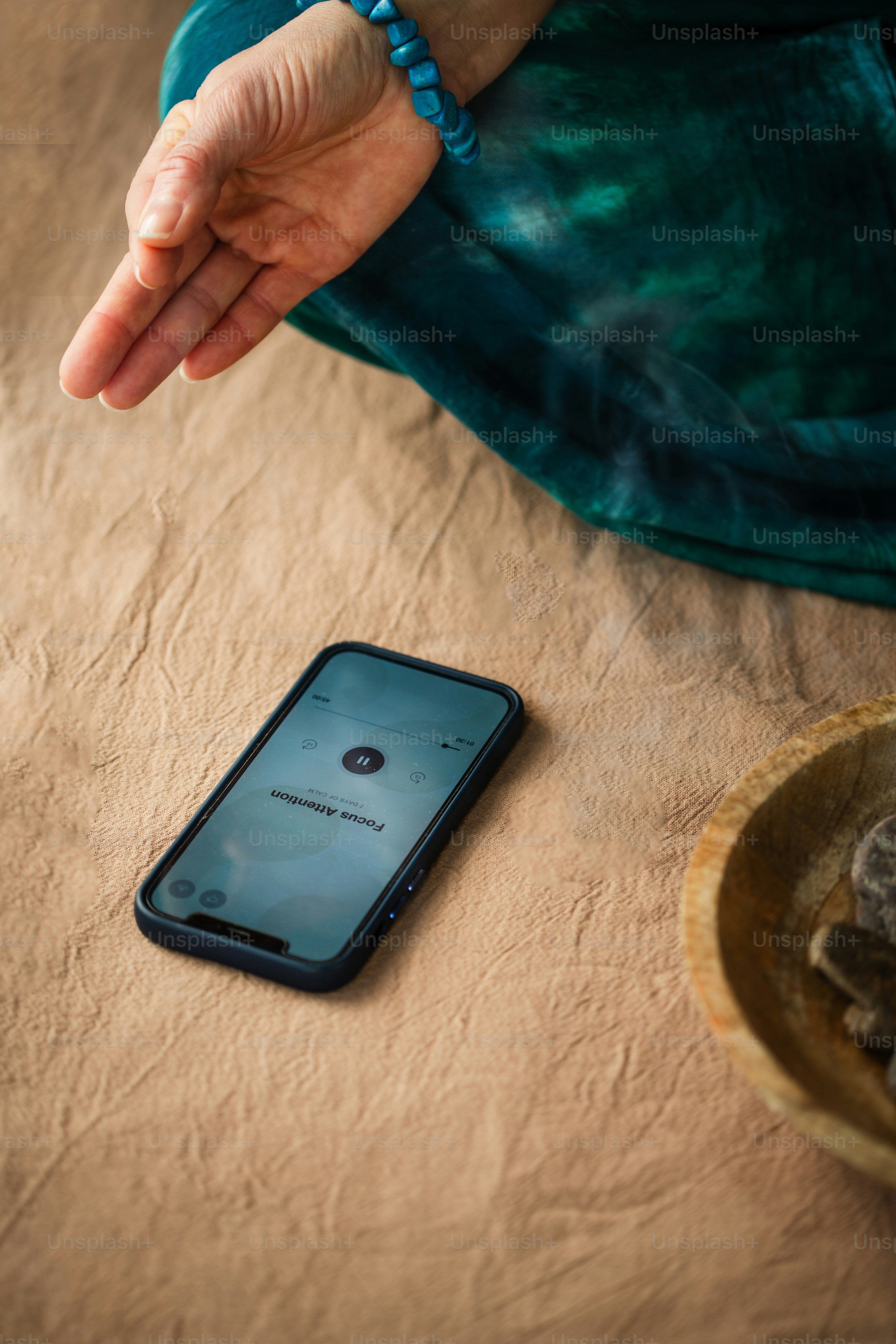 A person meditates with phone on the ground.