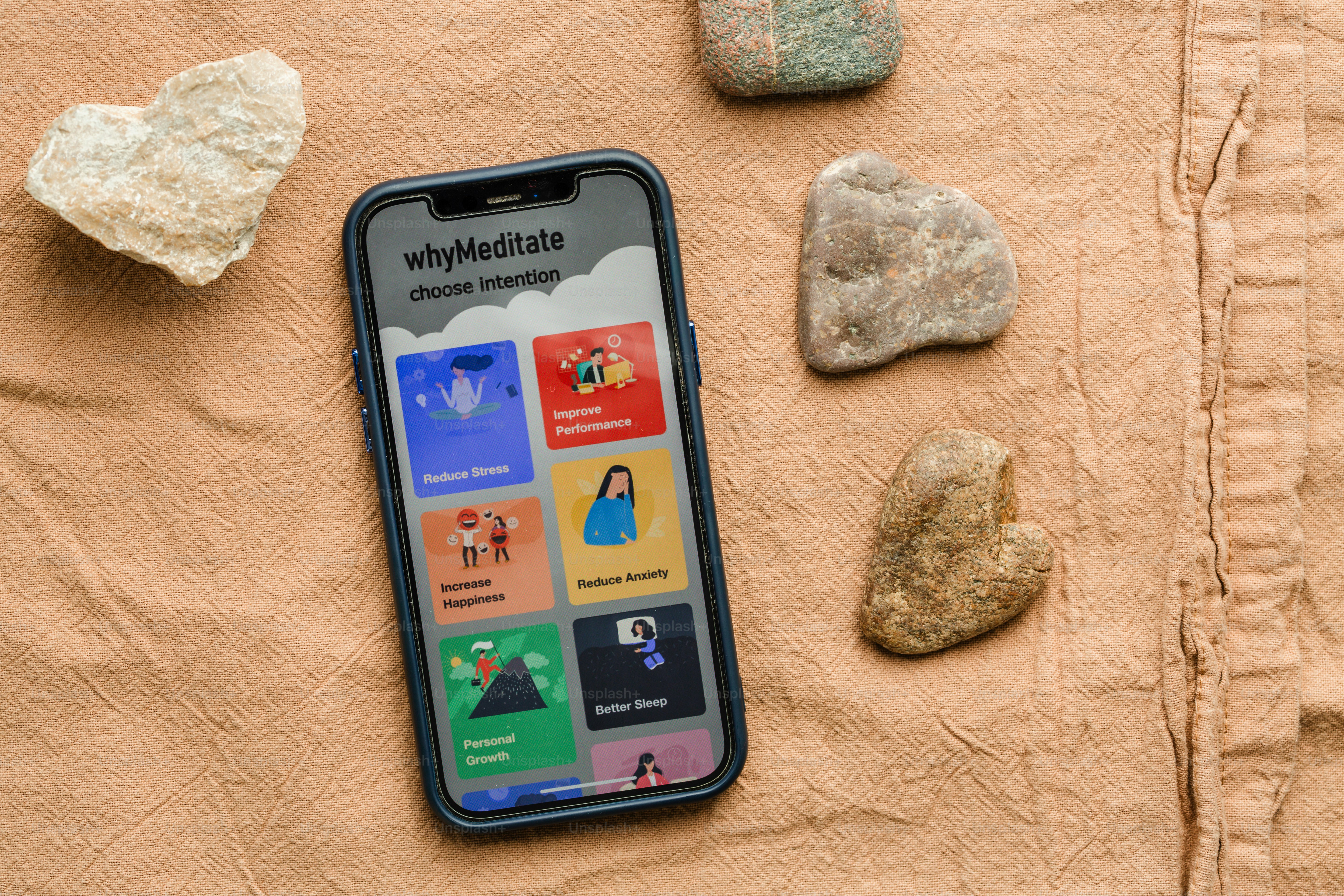 Smartphone displays a meditation app among stones.