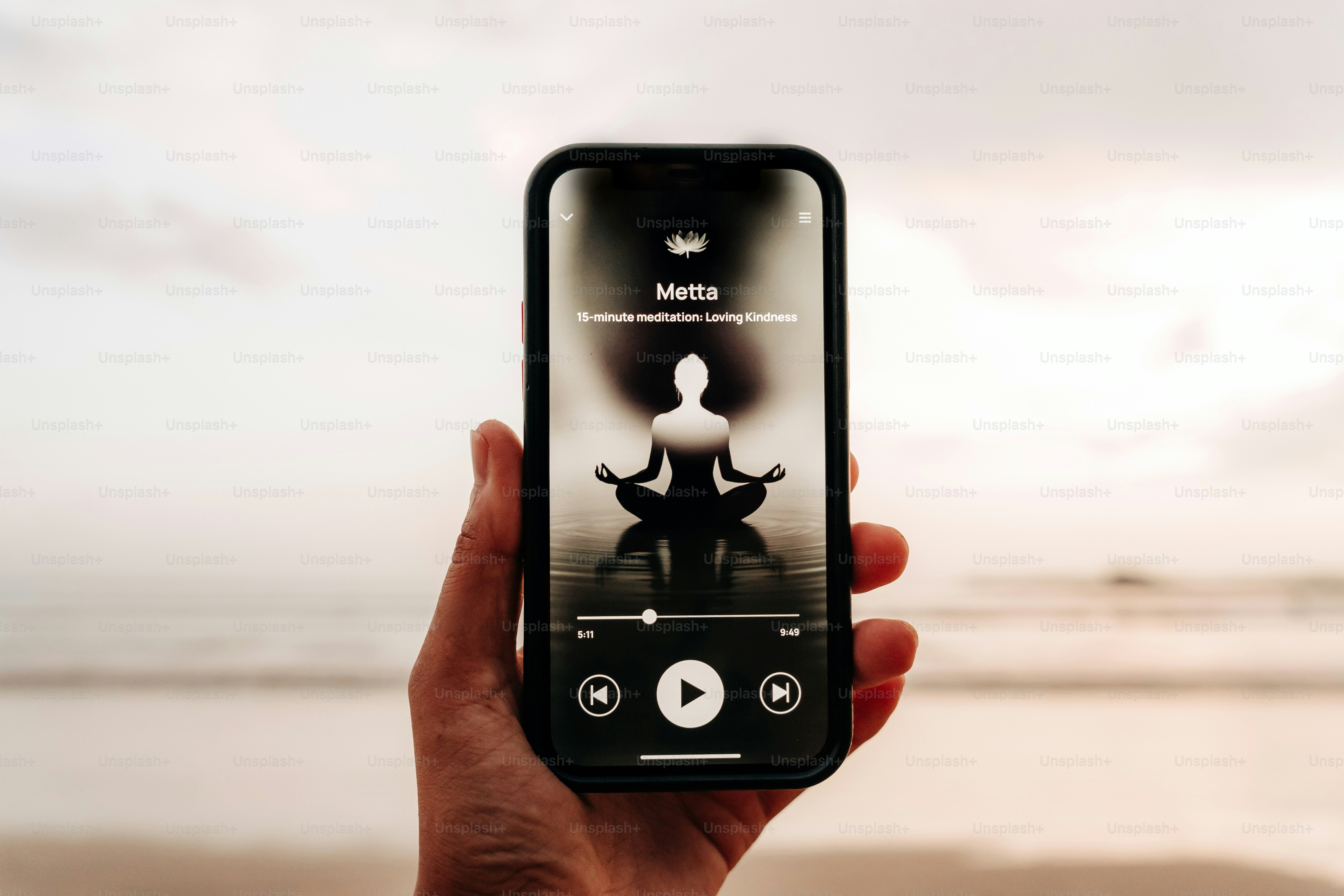 Eine Hand hält ein Telefon mit einer Meditations-App.