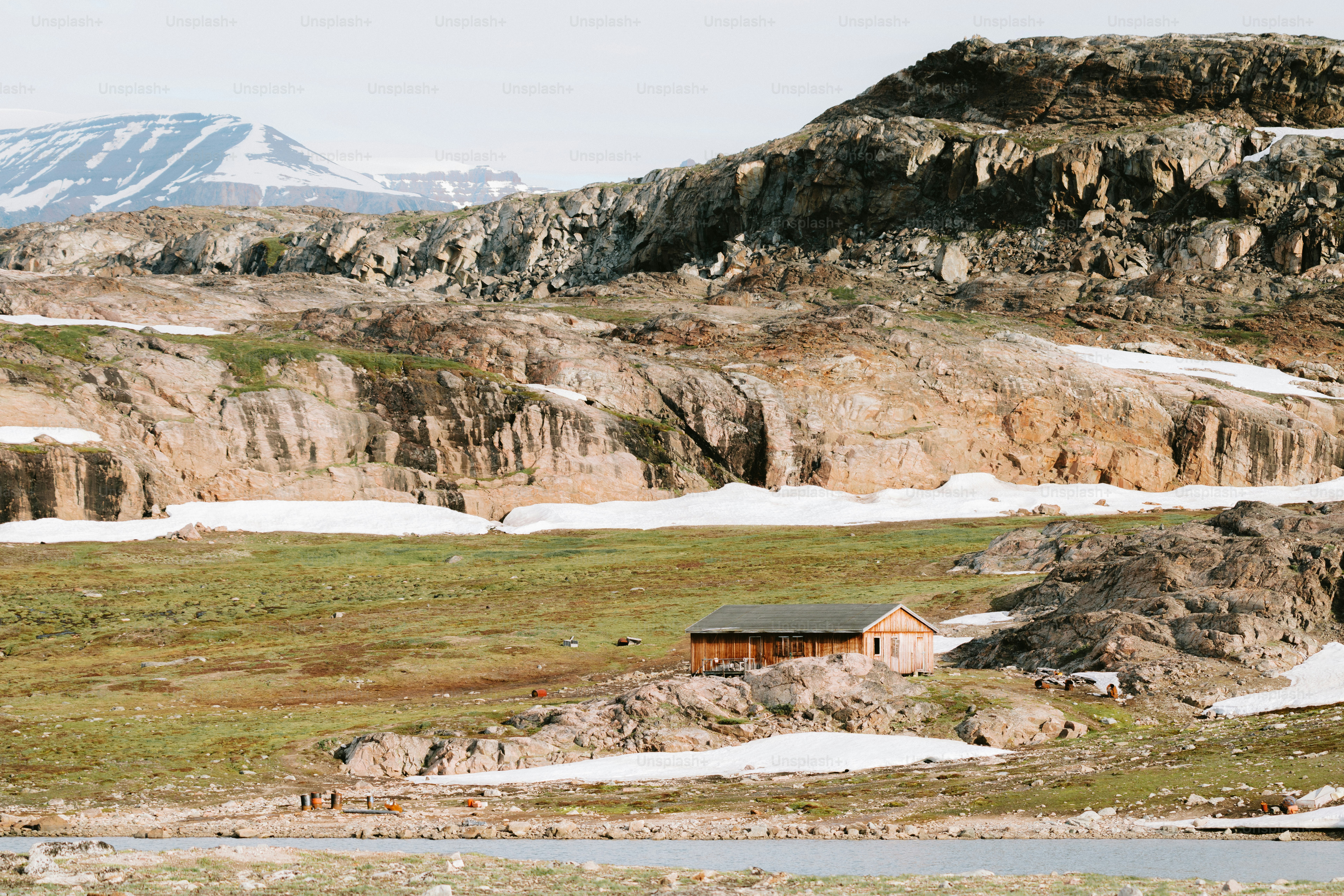 A cabin sits in a rocky, snowy landscape.