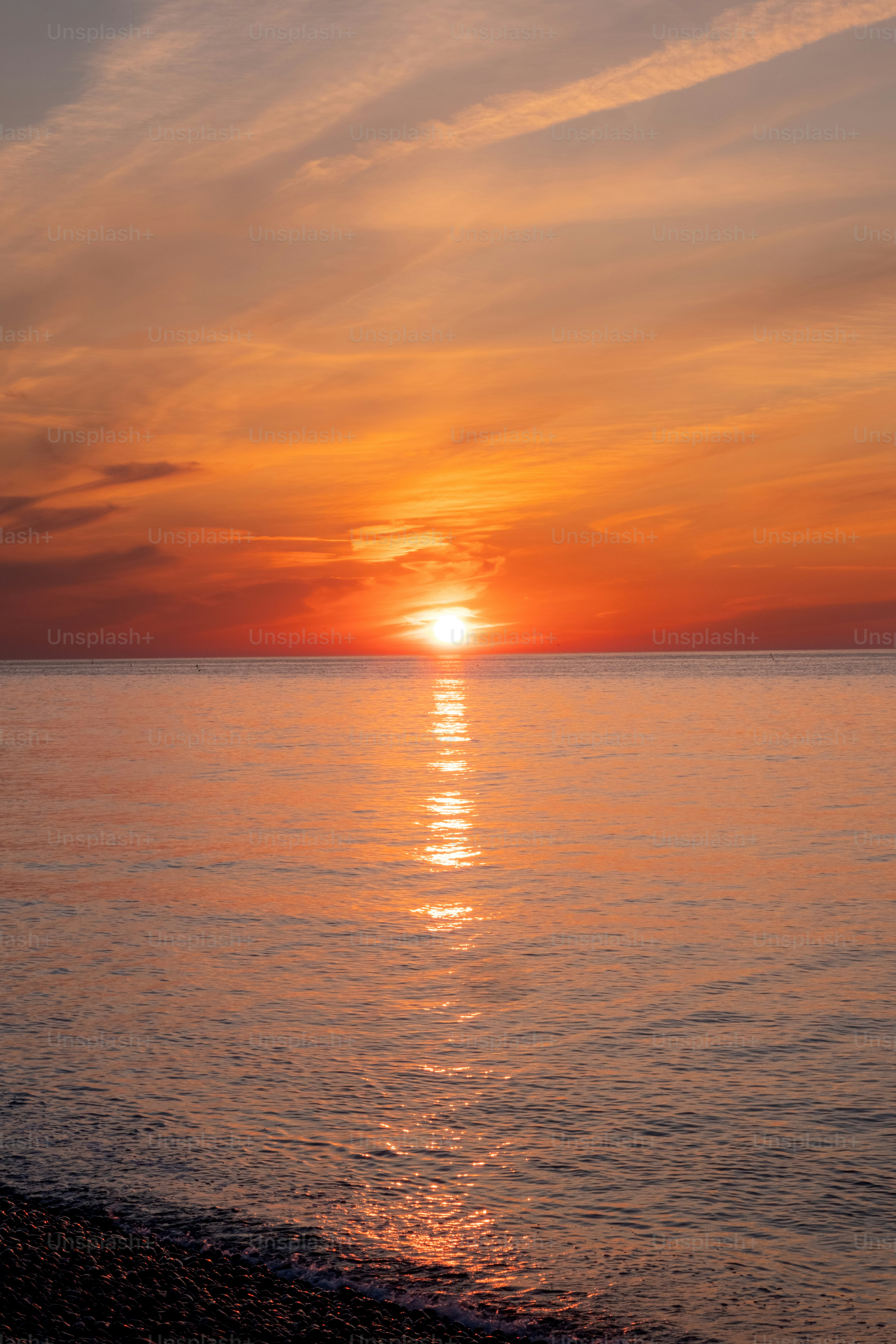 The sun sets over the calm ocean.