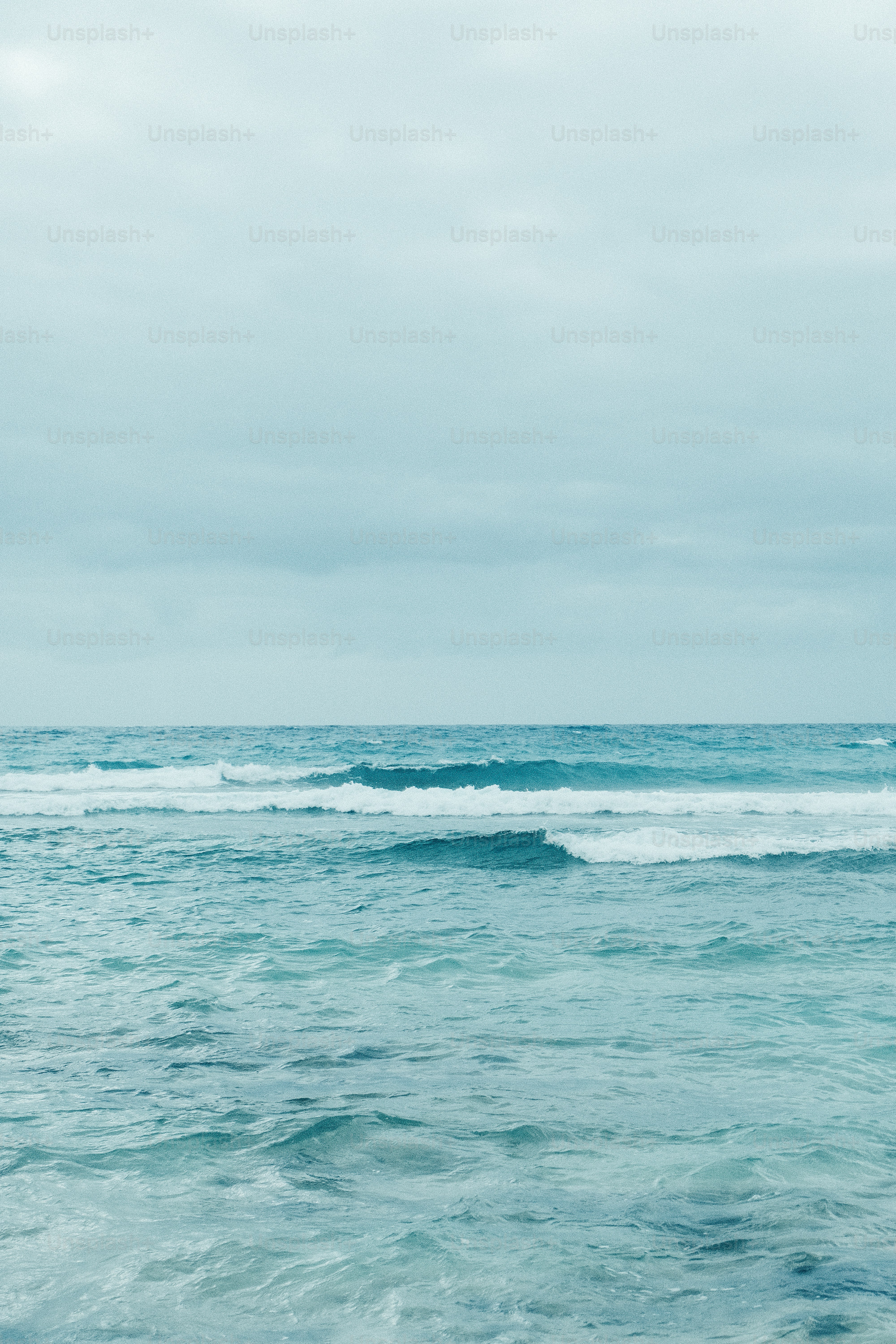 Ocean waves under a cloudy, blue sky.