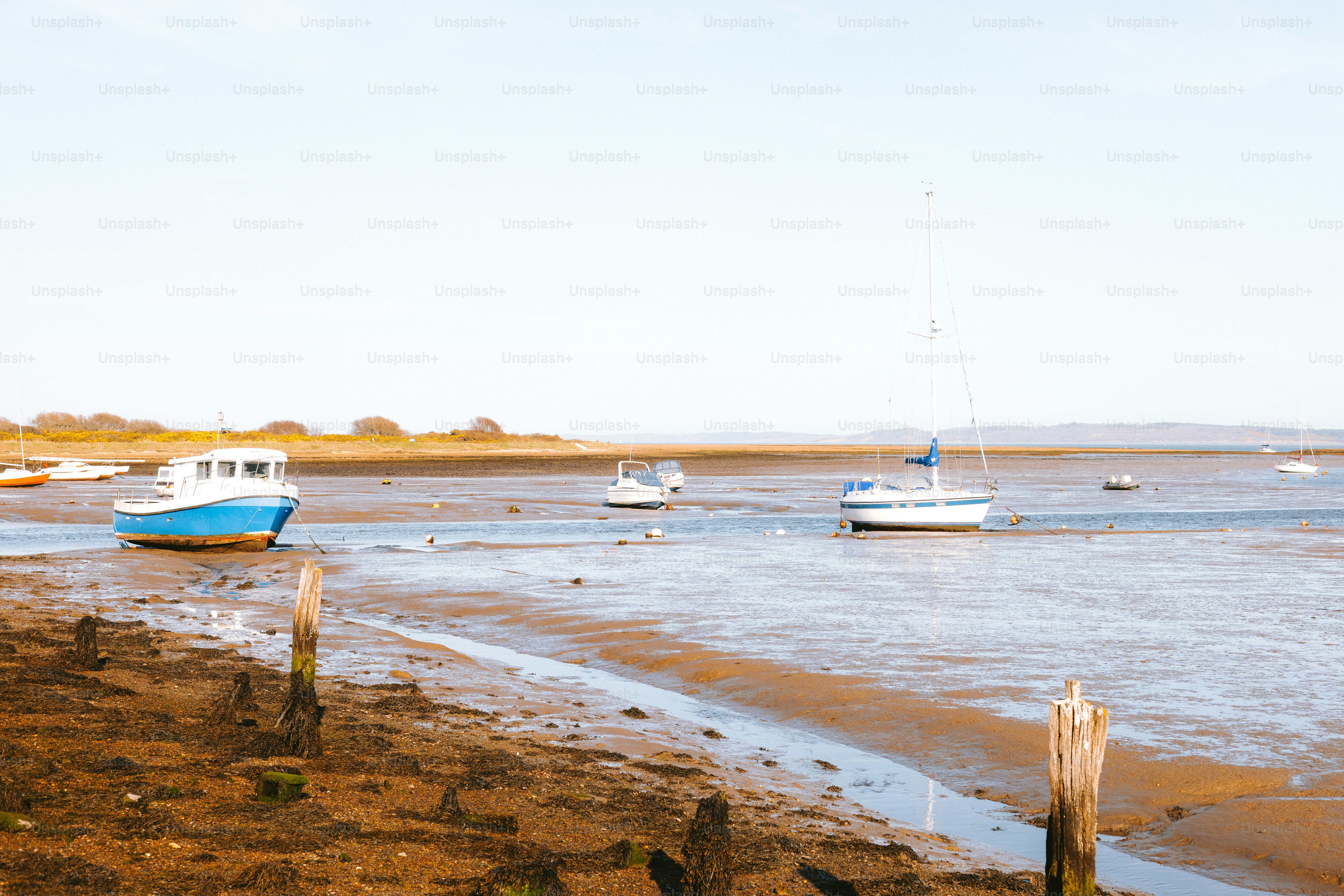 Boats rest on a muddy shore at low tide.