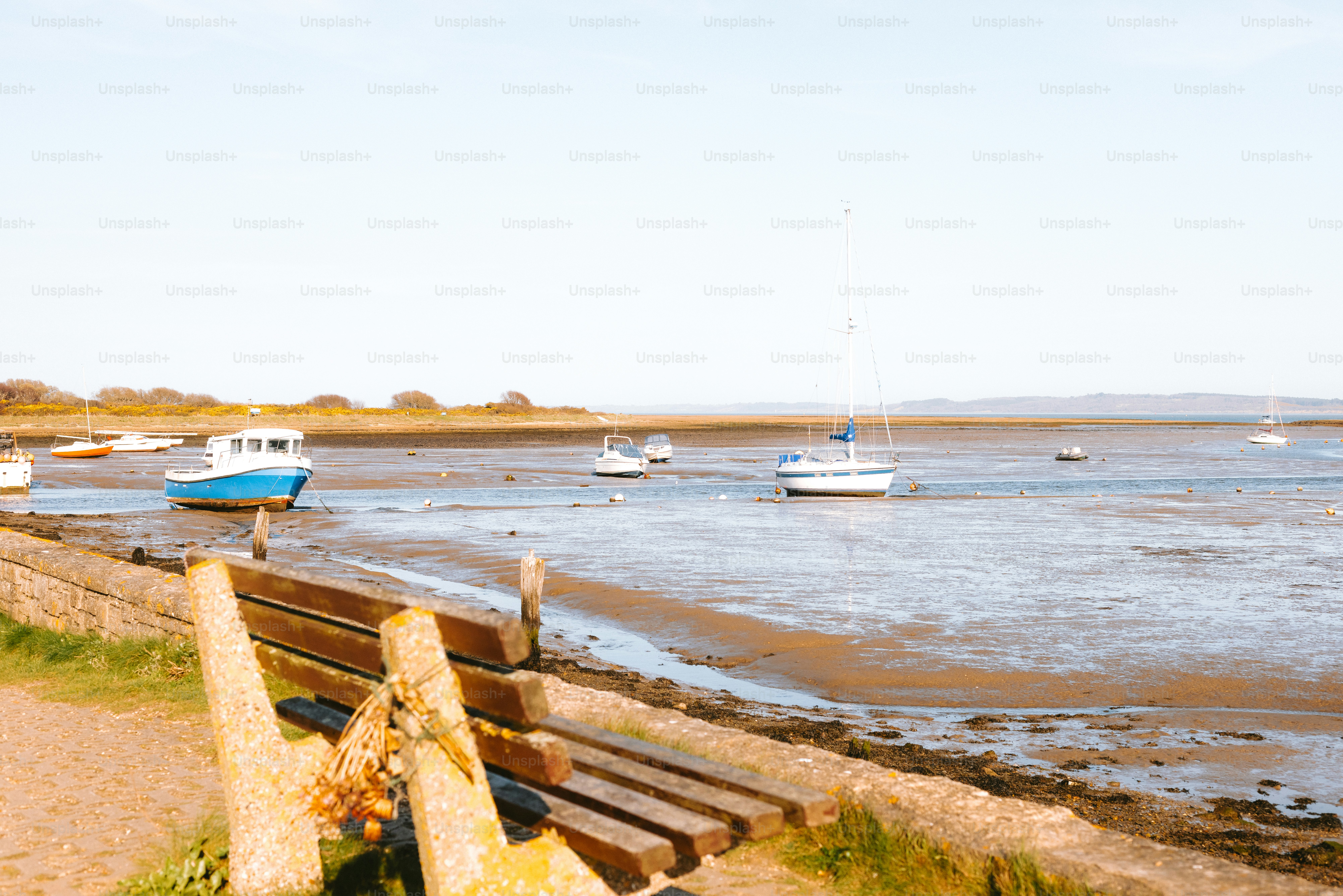 Boats are docked near a muddy beach at low tide.