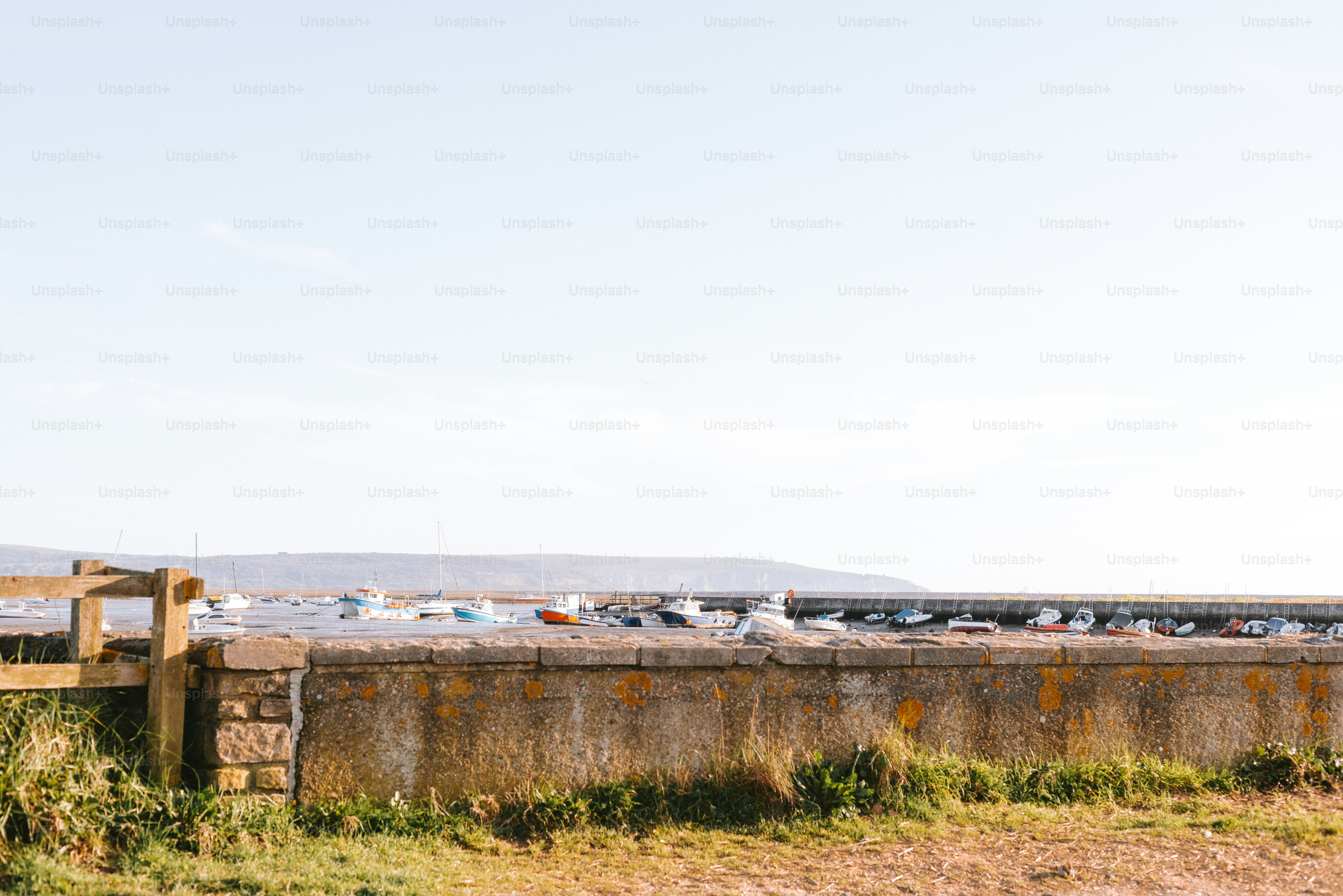 A seaside wall and gate with boats in the background.