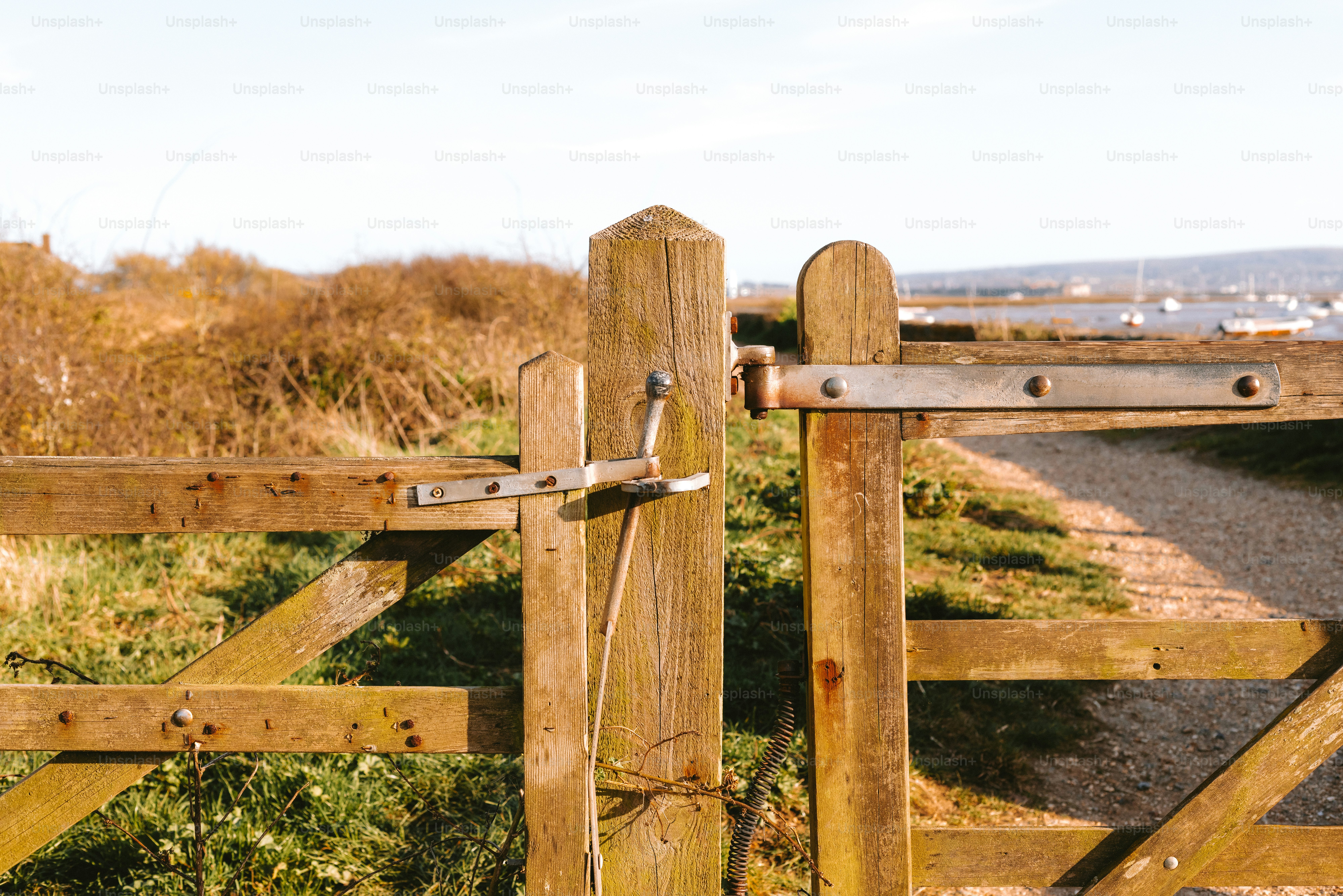 A wooden gate stands open in a sunny field.