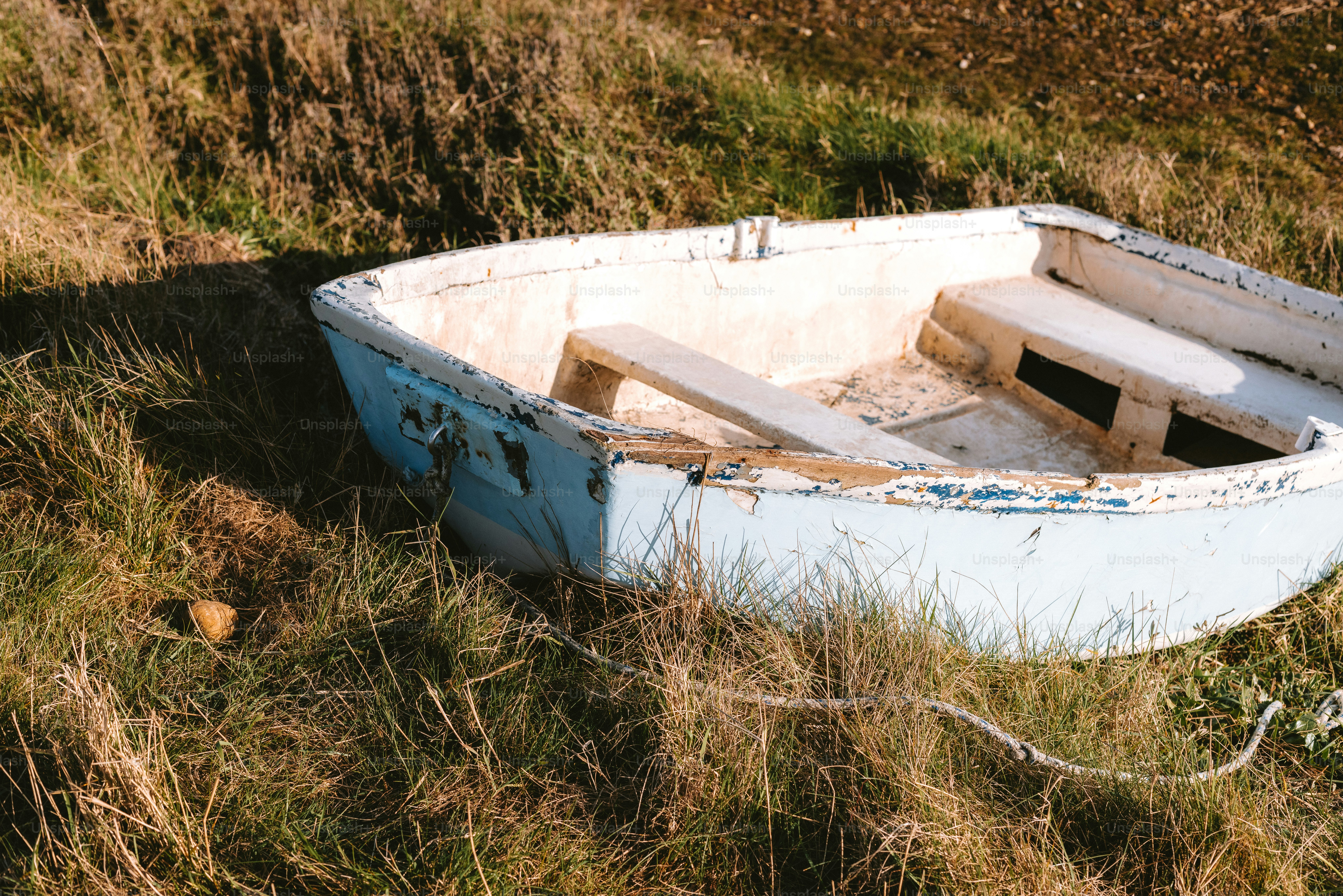 An old rowboat sits in grassy fields.