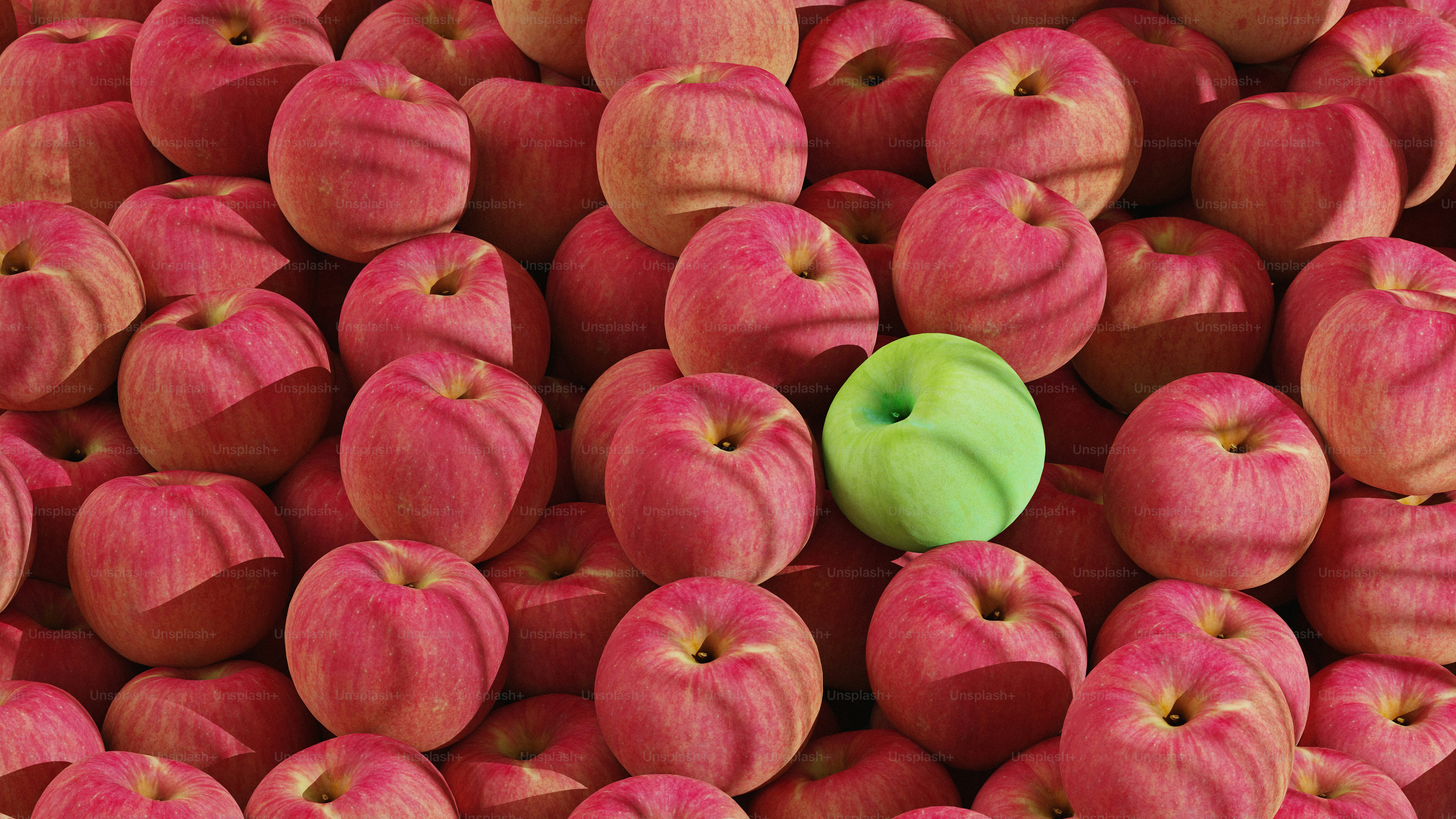 Una manzana verde entre muchas manzanas rojas.