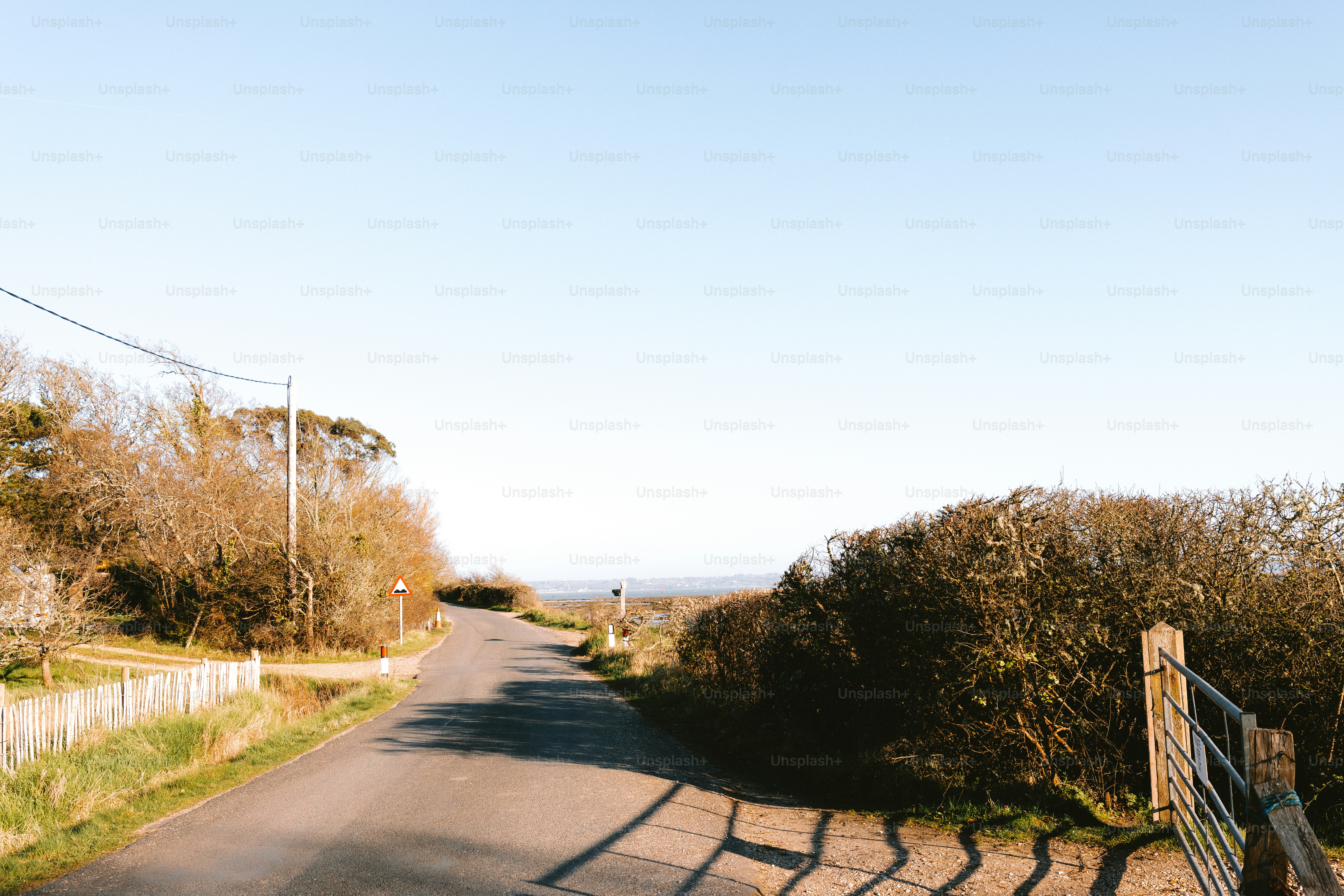 A road leads to the ocean under a clear sky.