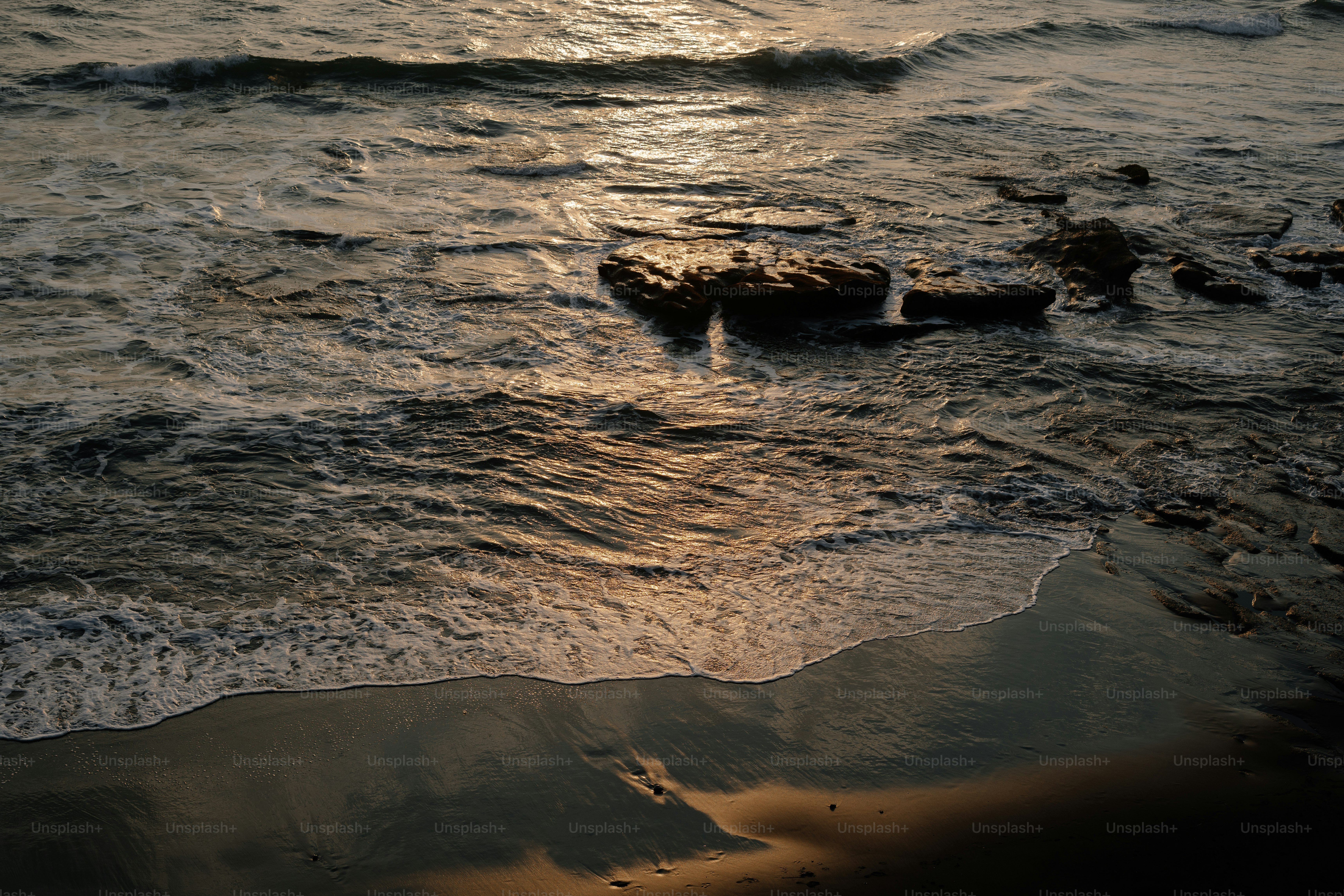 Waves crash gently on the shore at sunset.