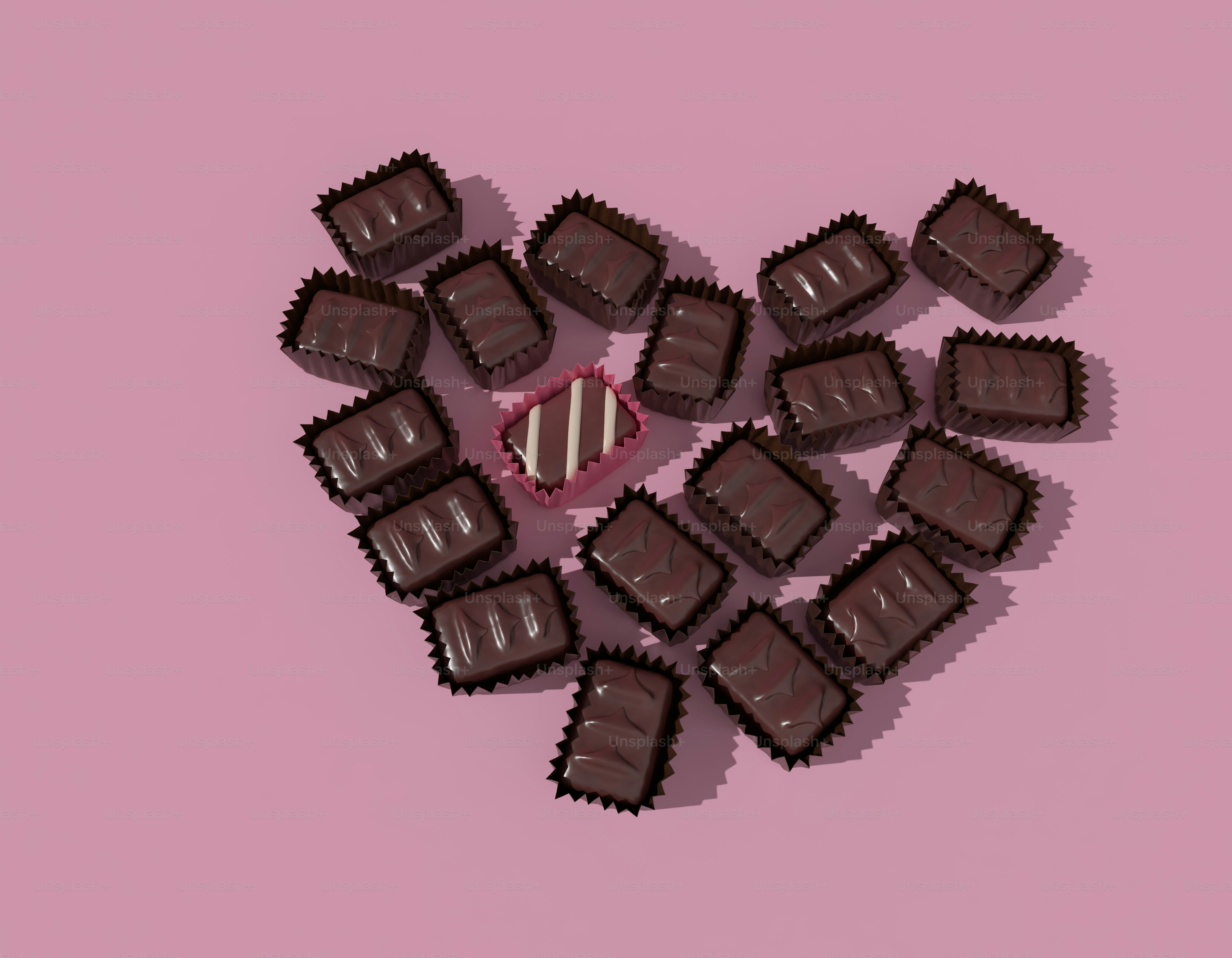Chocolates dispostos em um coração sobre um fundo rosa.