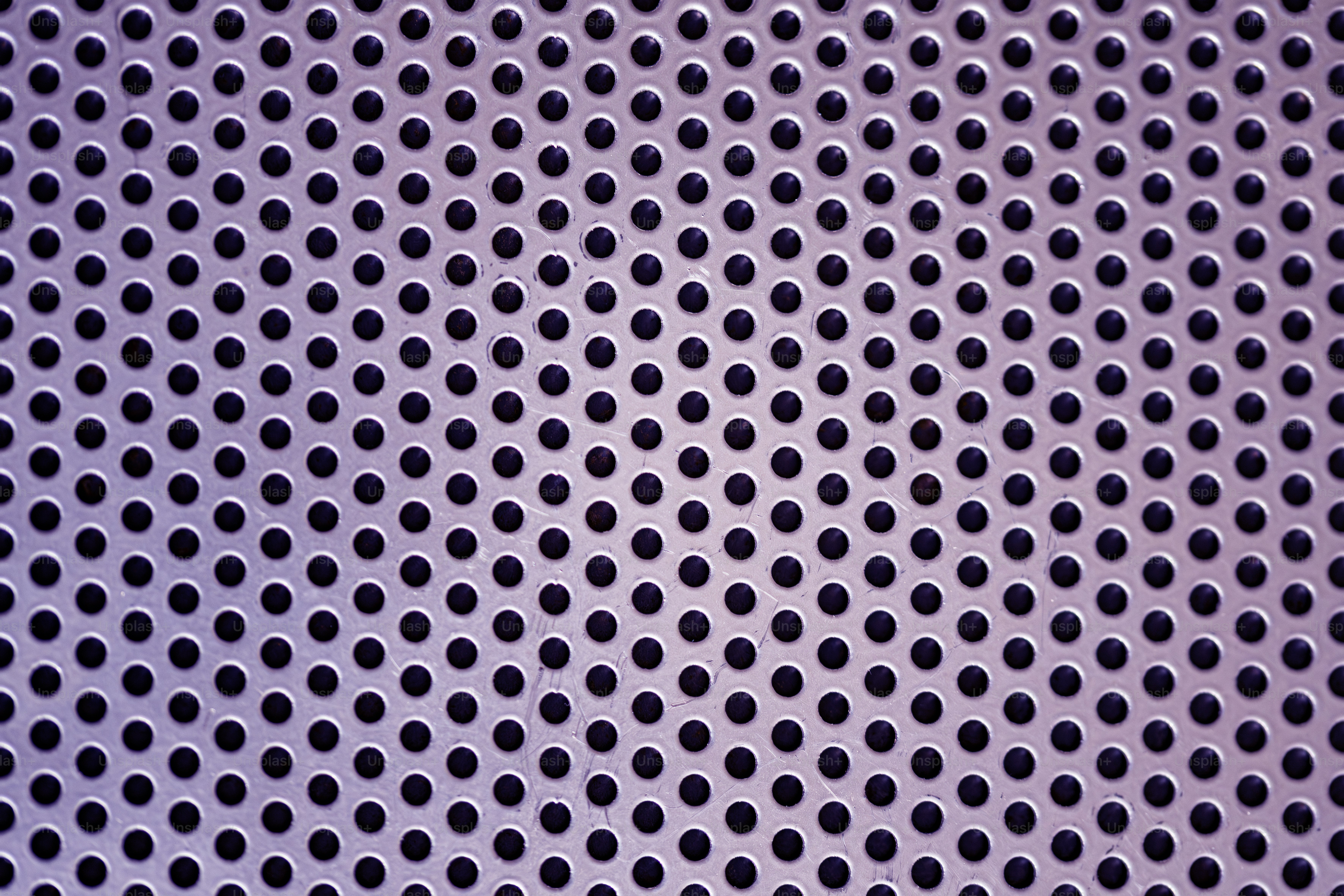 A pattern of small, evenly spaced holes. photo – Texture Image on Unsplash