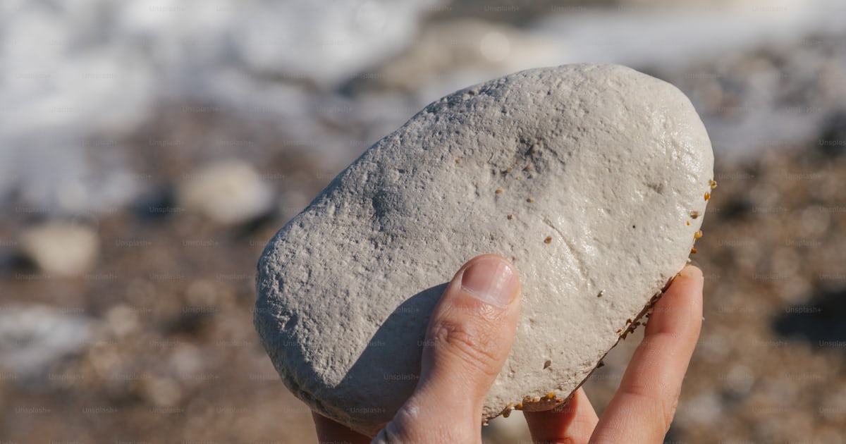A hand holds a light-colored rock. photo – Texture Image on Unsplash