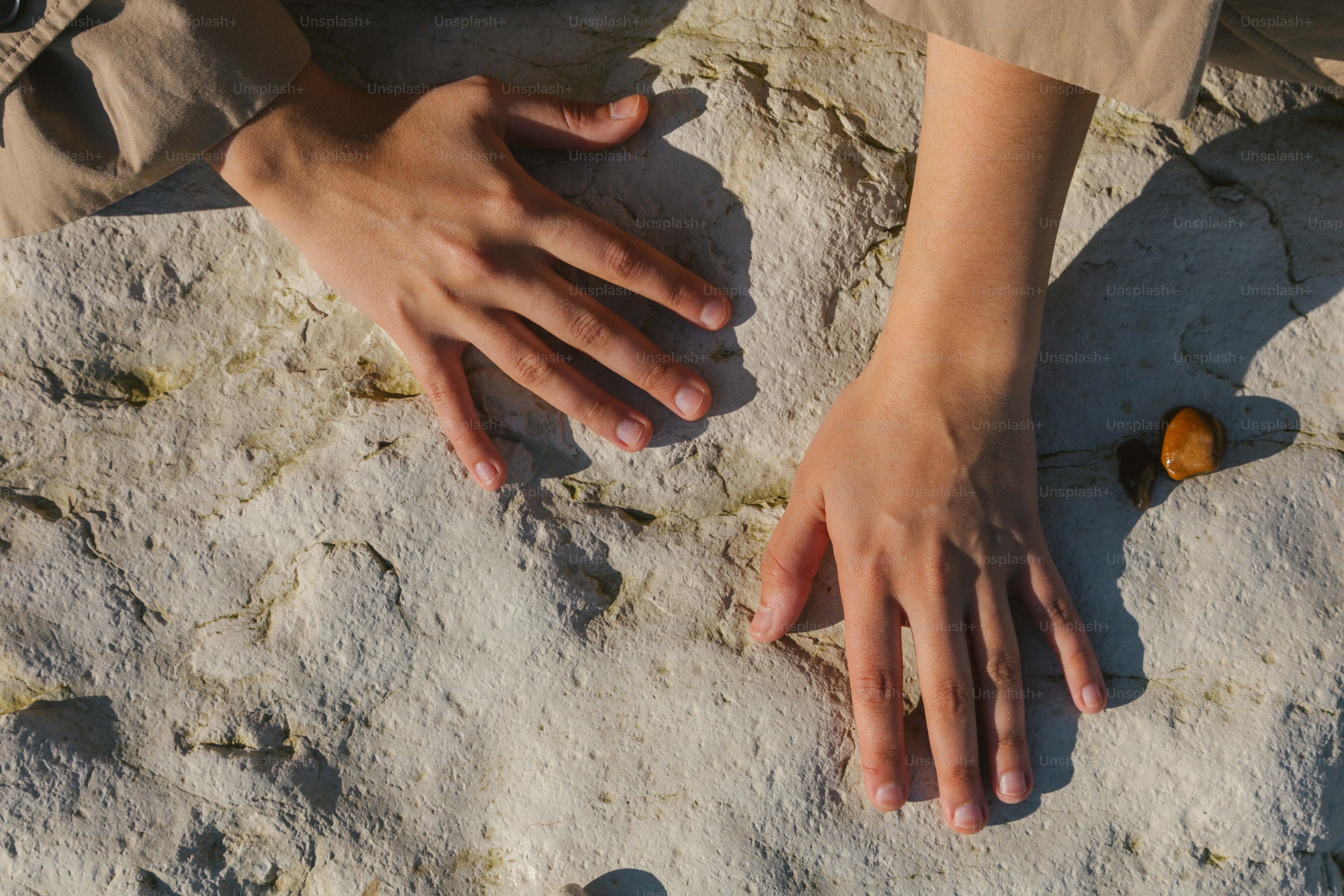 Die Hände ruhen auf einer rauen, strukturierten Oberfläche.