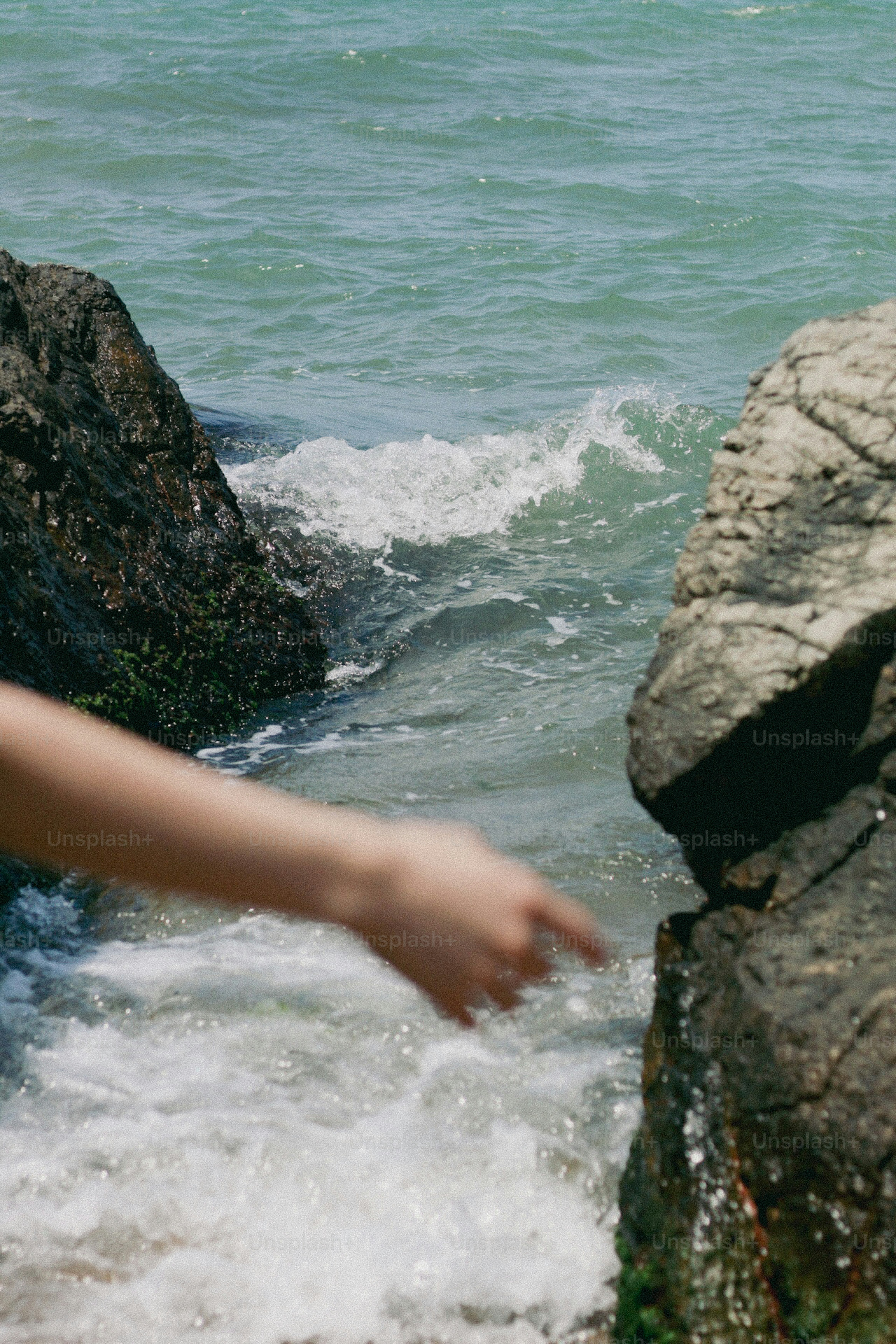 A hand reaches towards the sea.