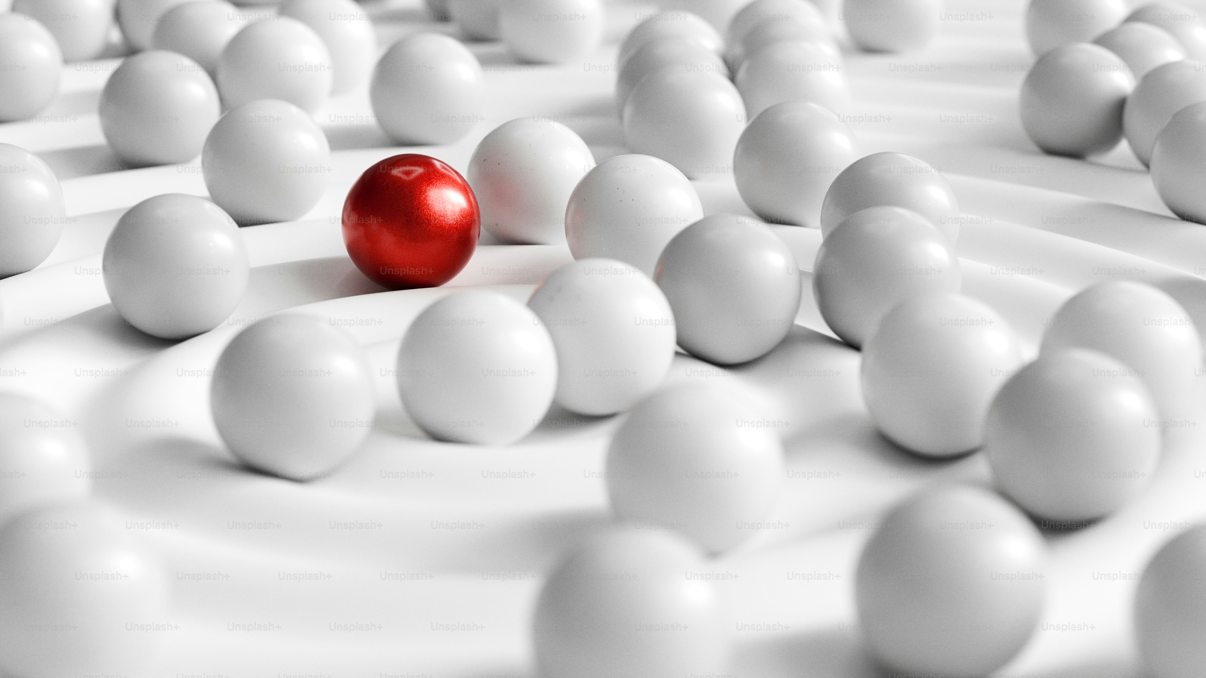 A red ball stands out among many white ones.