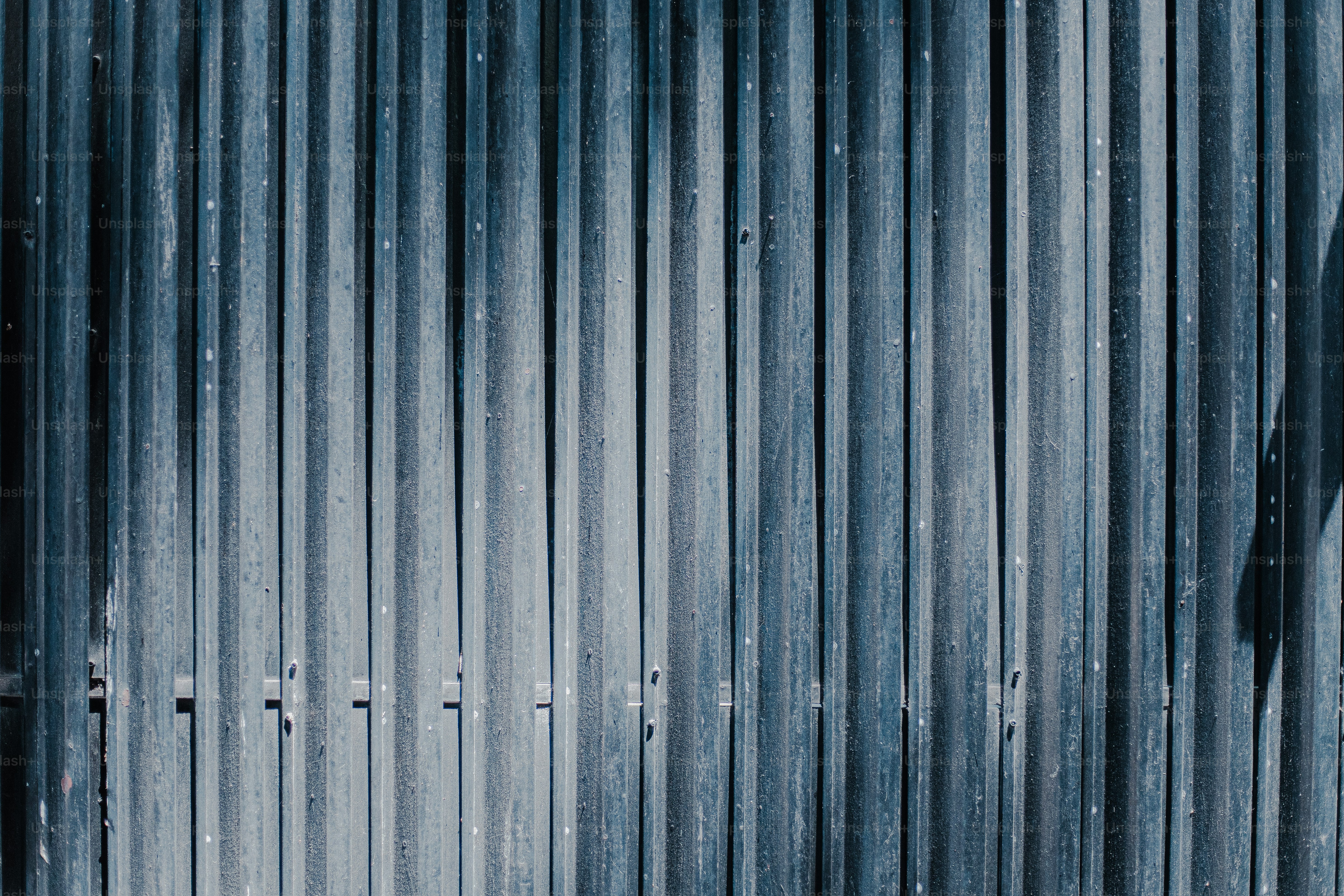 The image shows a textured, vertical metal gate.