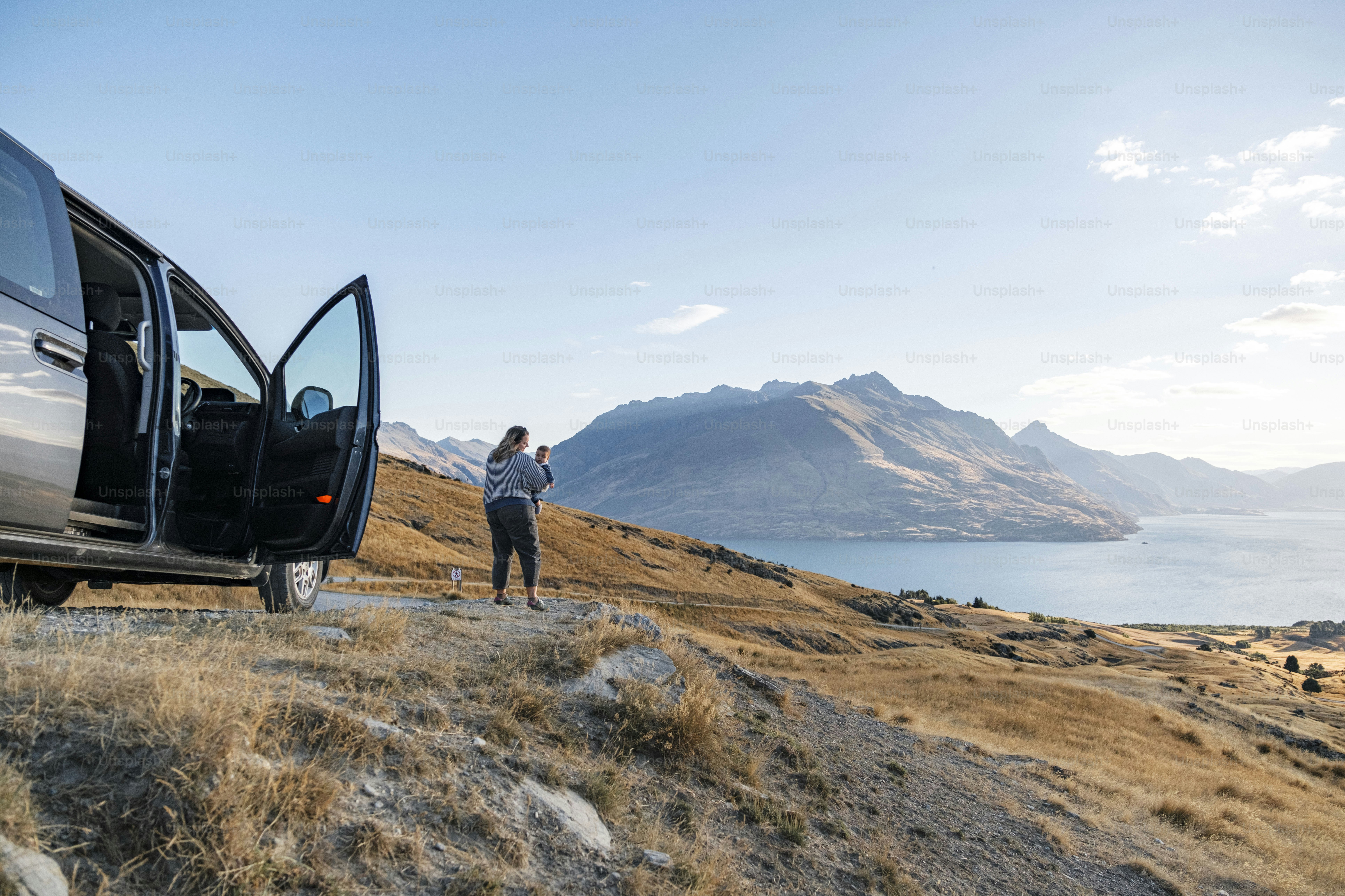 Die Person genießt eine malerische Aussicht in der Nähe von Fahrzeug, See und Bergen.