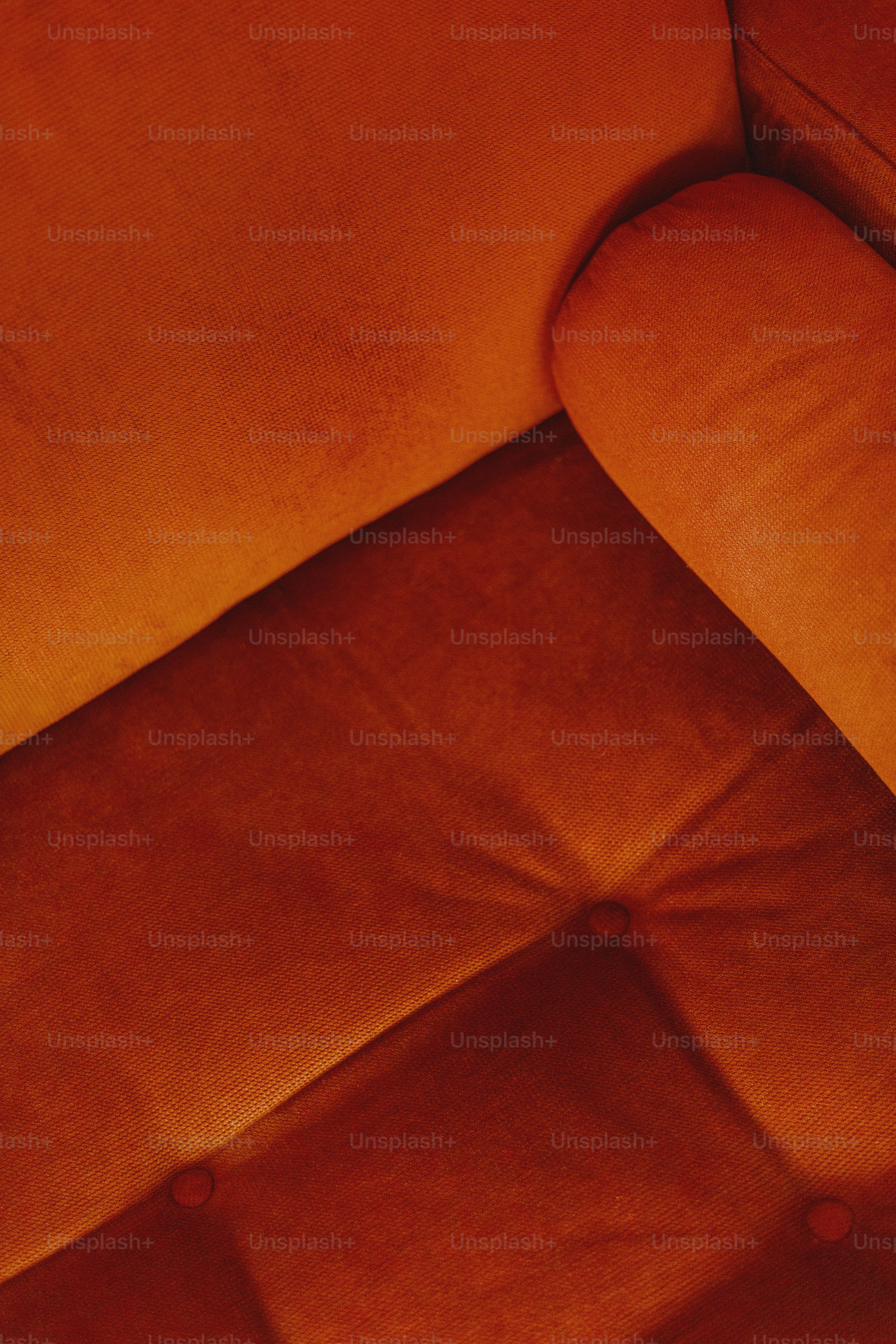 Orange velvet couch with a tufted design.