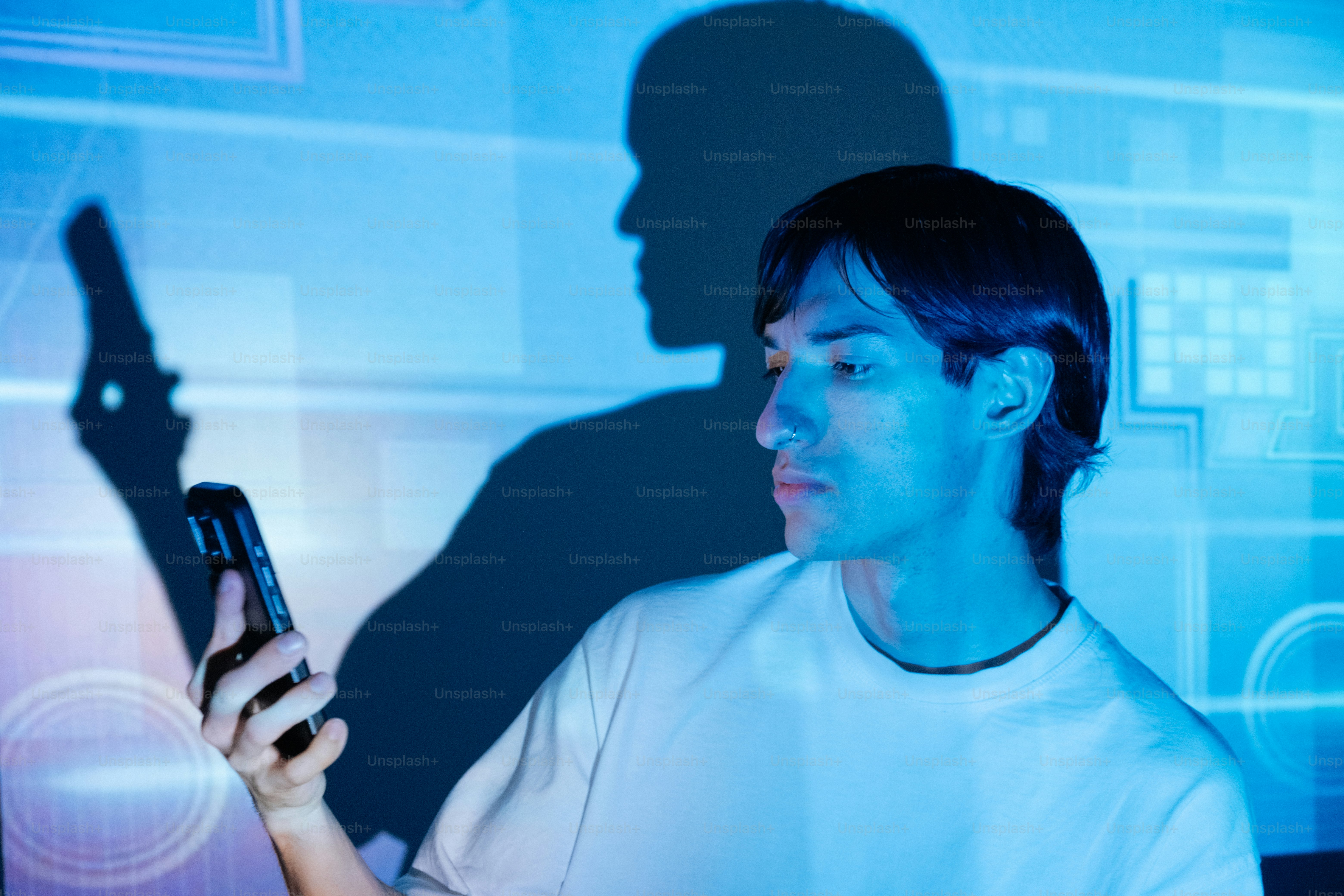 A man looks at his phone, backlit by blue light.