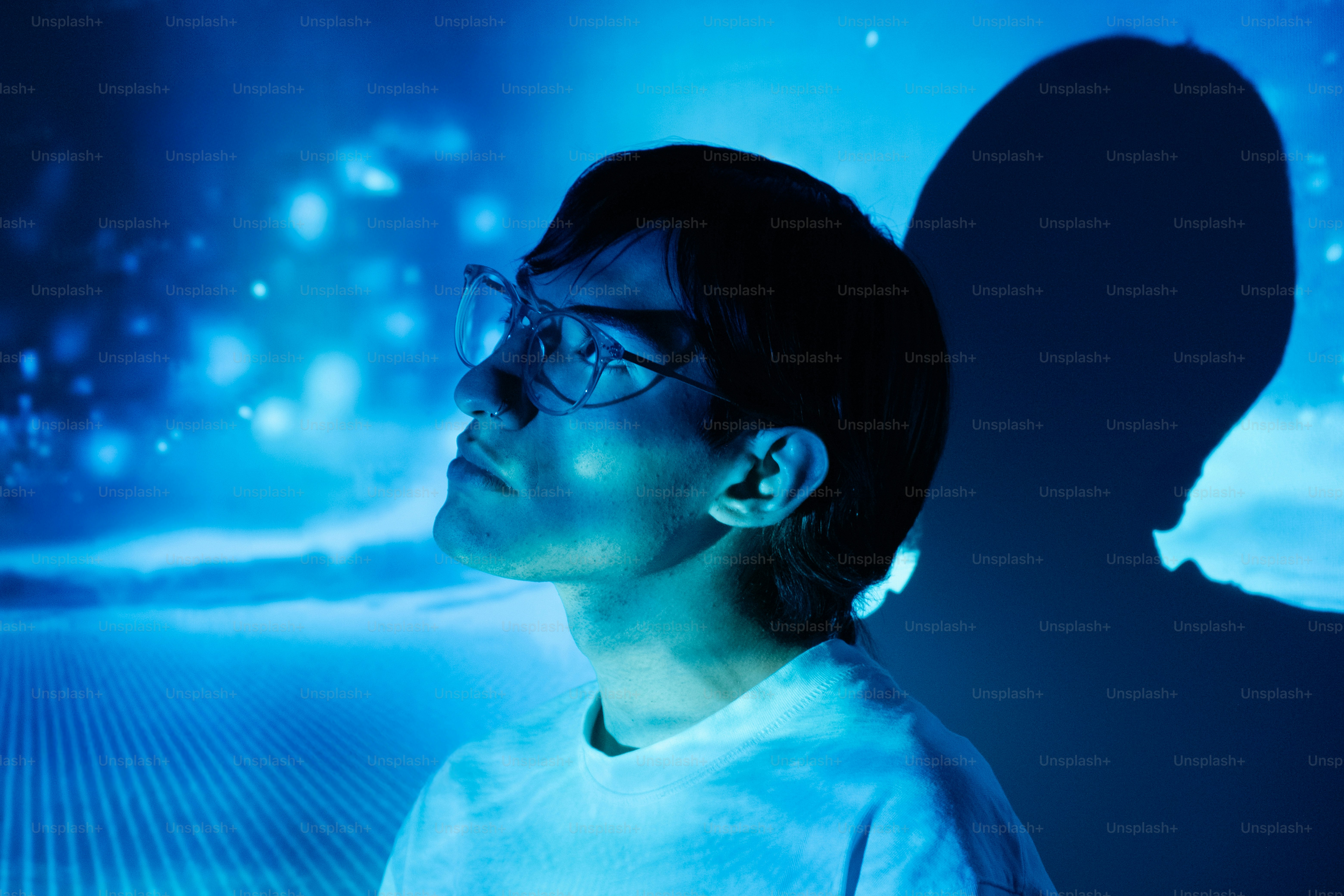 Man looks up, bathed in blue light.