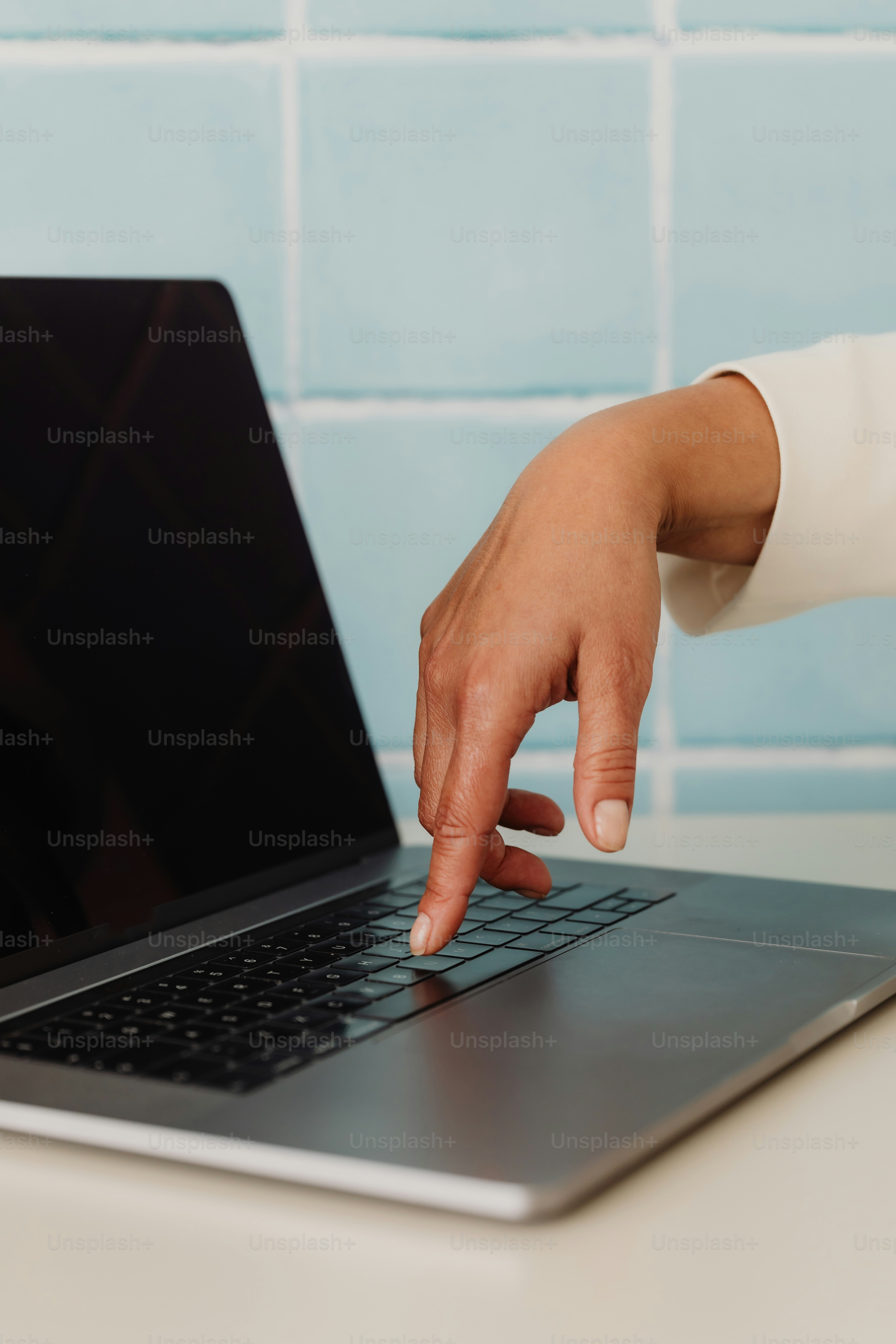 A hand taps a key on a laptop.