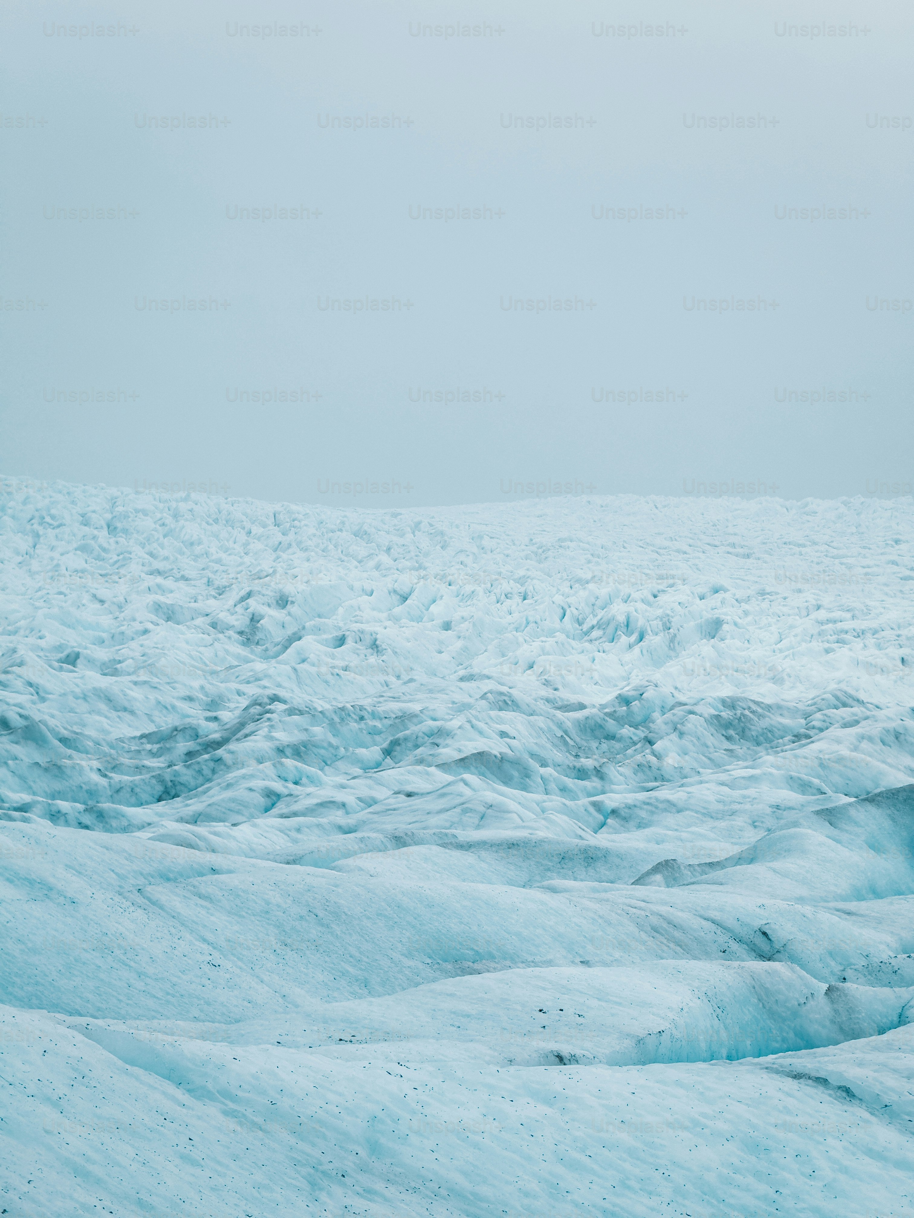 Un vaste glacier s’étend sur un paysage brumeux.