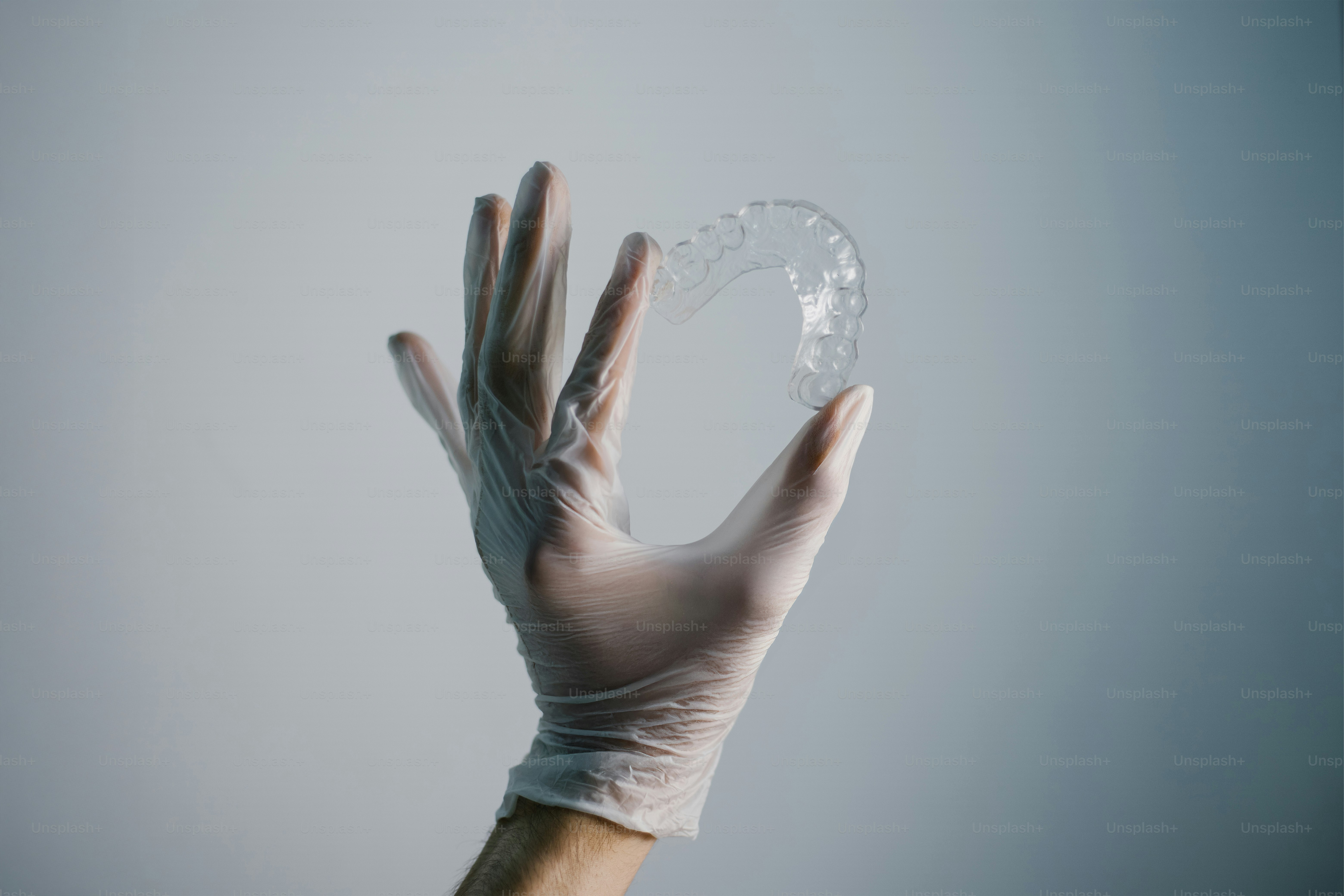 A gloved hand holds a clear orthodontic retainer