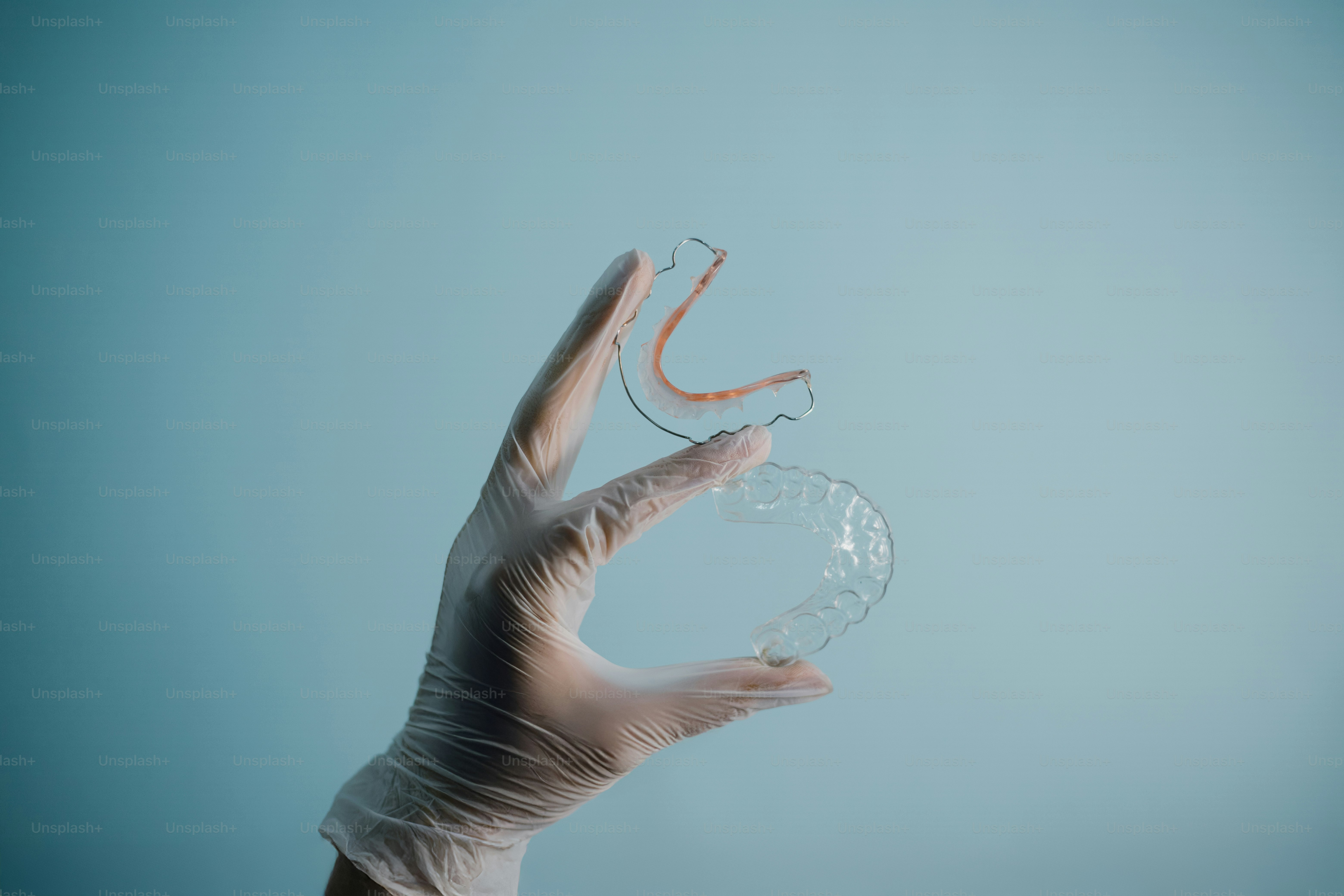 Una mano sostiene alineadores dentales transparentes