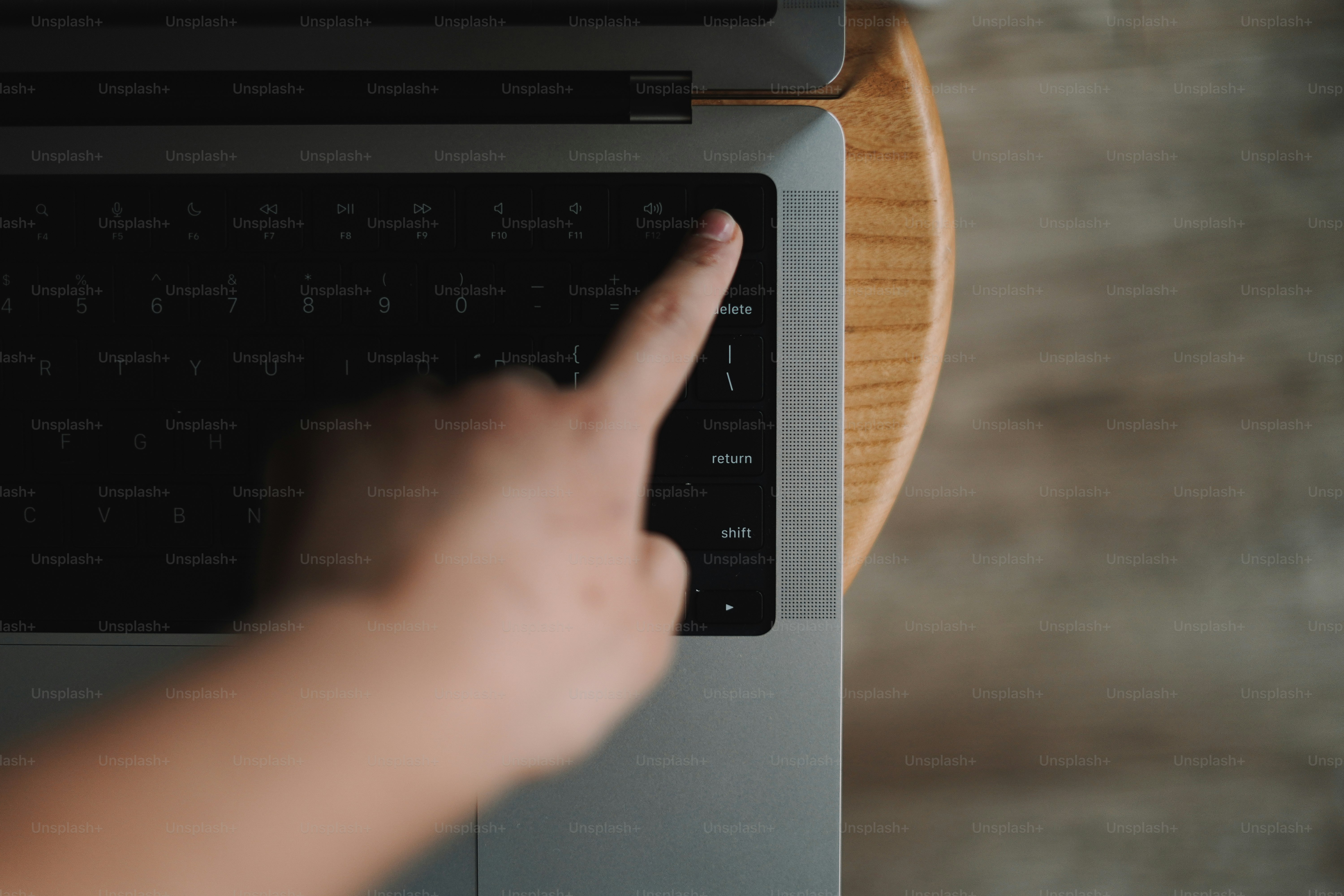 An anonymous finger points at a specific key on a laptop, emphasizing focus, input, and the tactile side of digital work.
