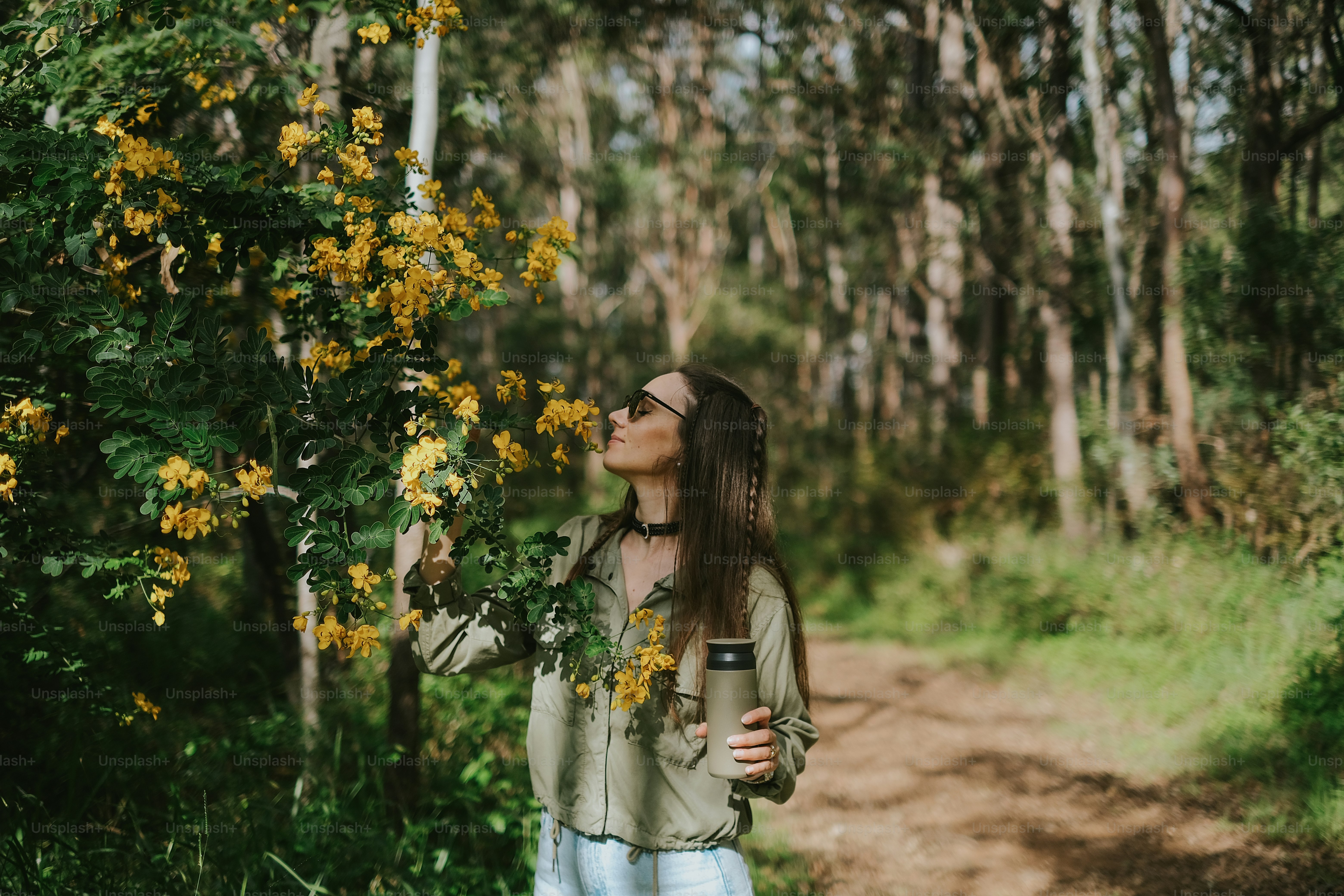 Woman enjoys the scent of flowers in the woods.