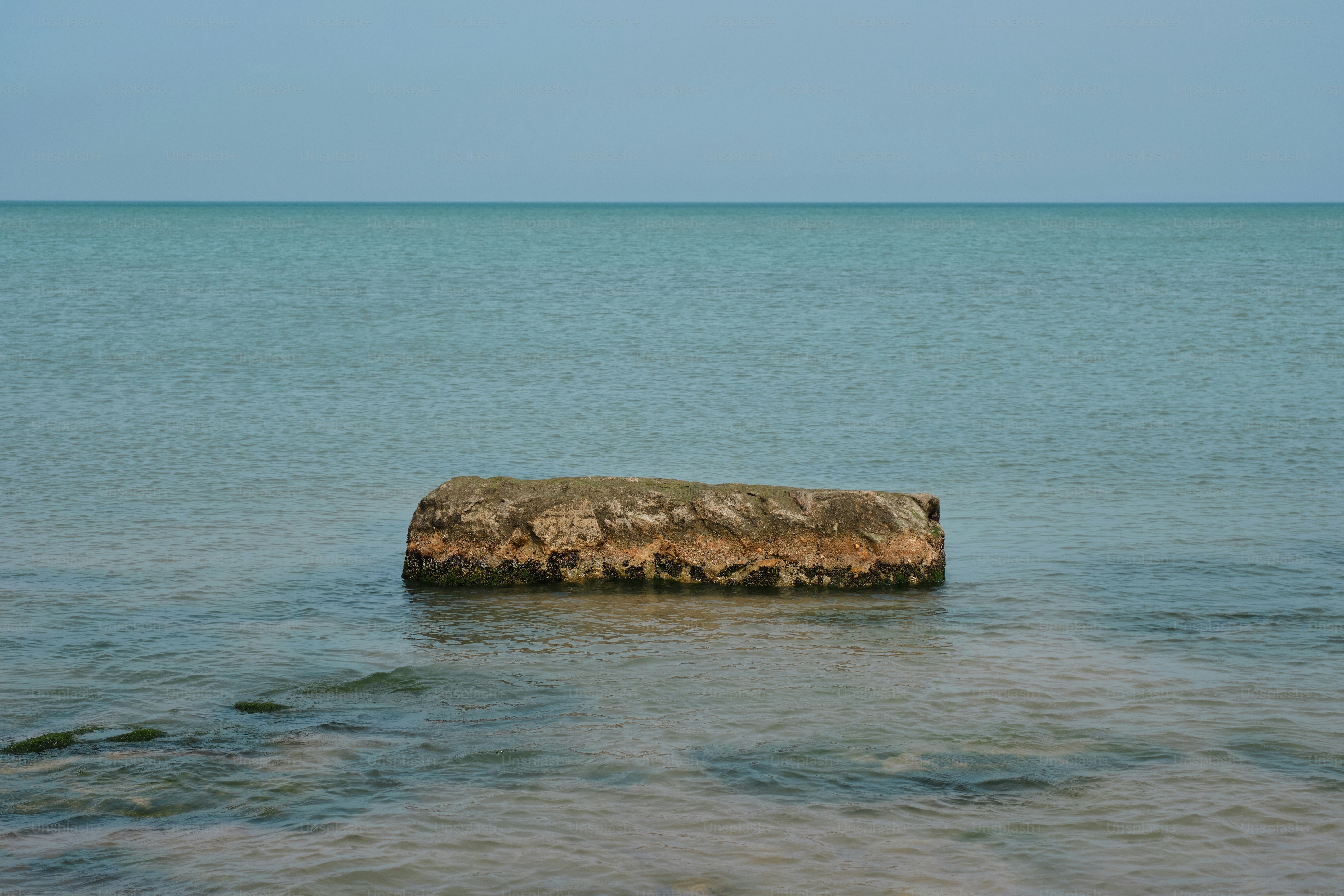 A concrete structure sits in calm, blue water.