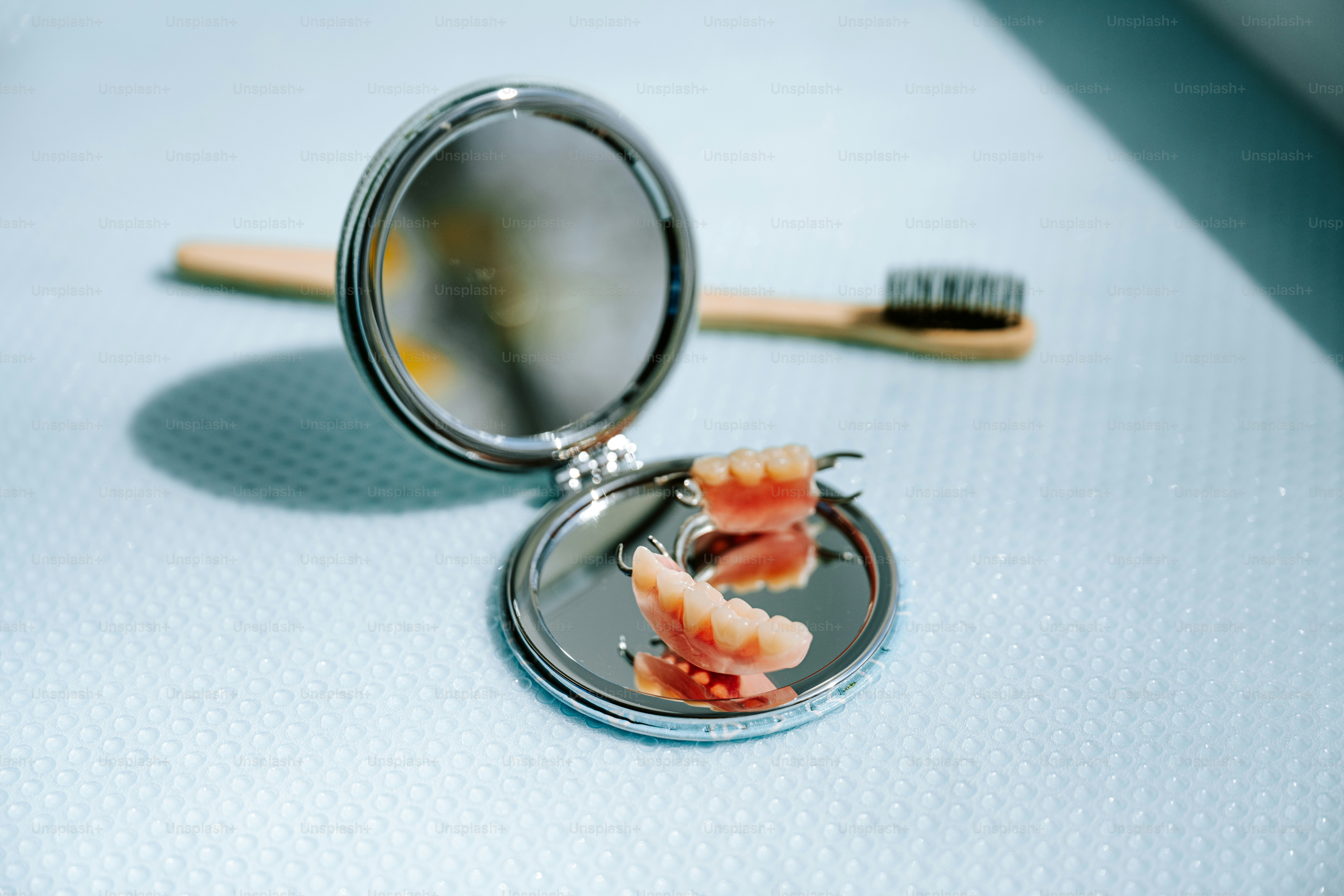Les prothèses dentaires sont dans un miroir avec une brosse à dents.