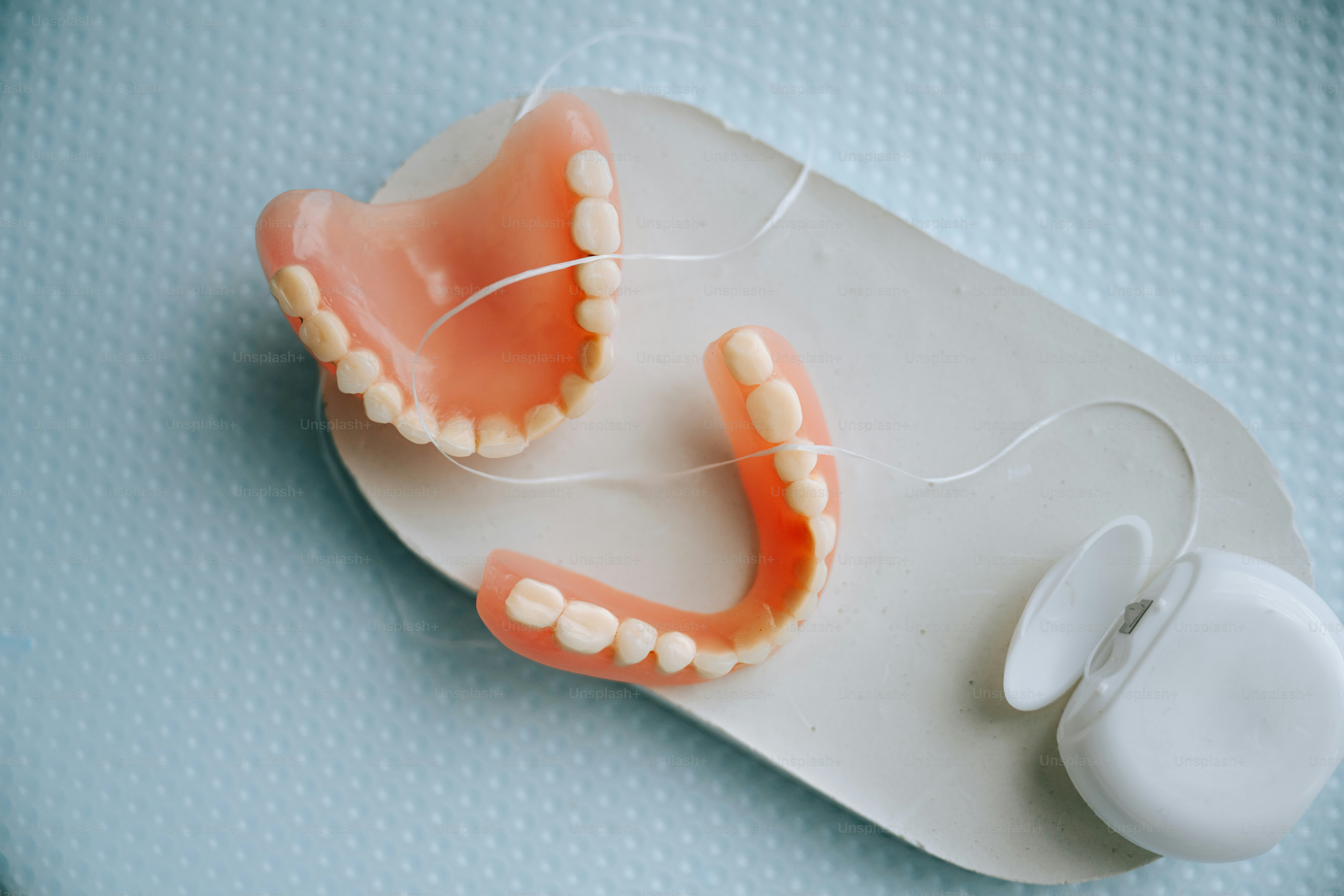Dentures and dental floss rest on a tray.