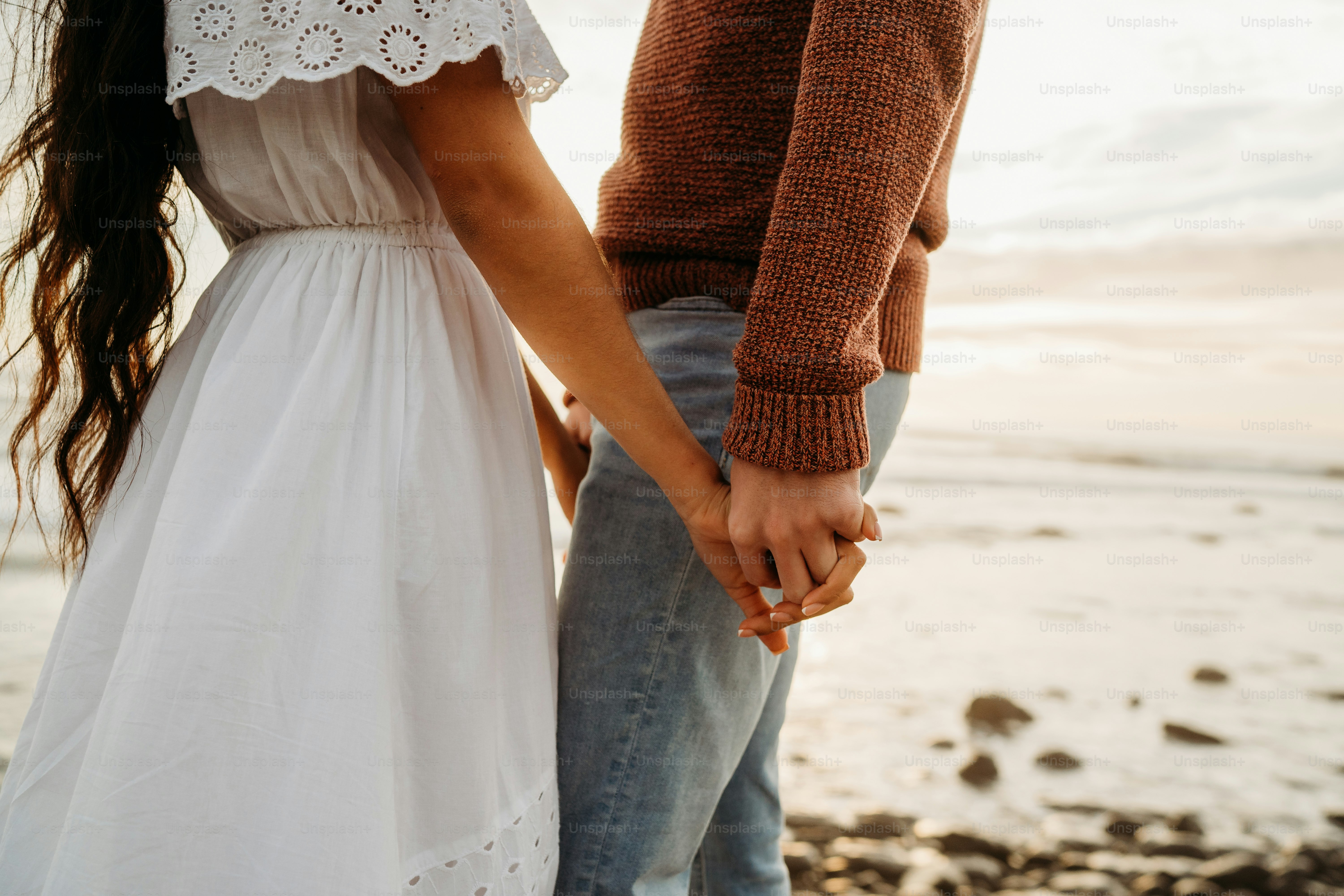 Couple holding hands together at the beach.