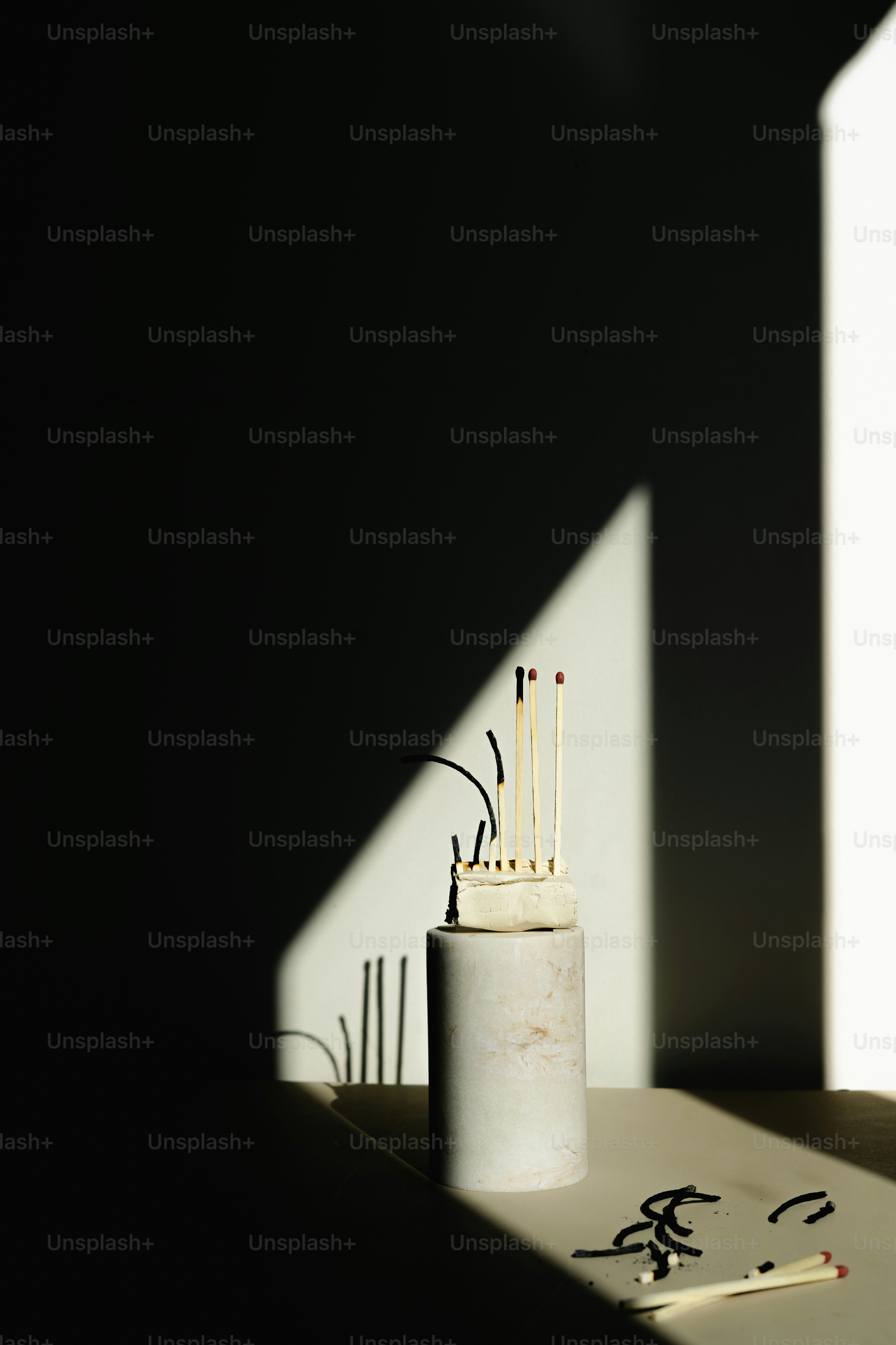 Matches are arranged on a minimalist cylindrical pedestal.