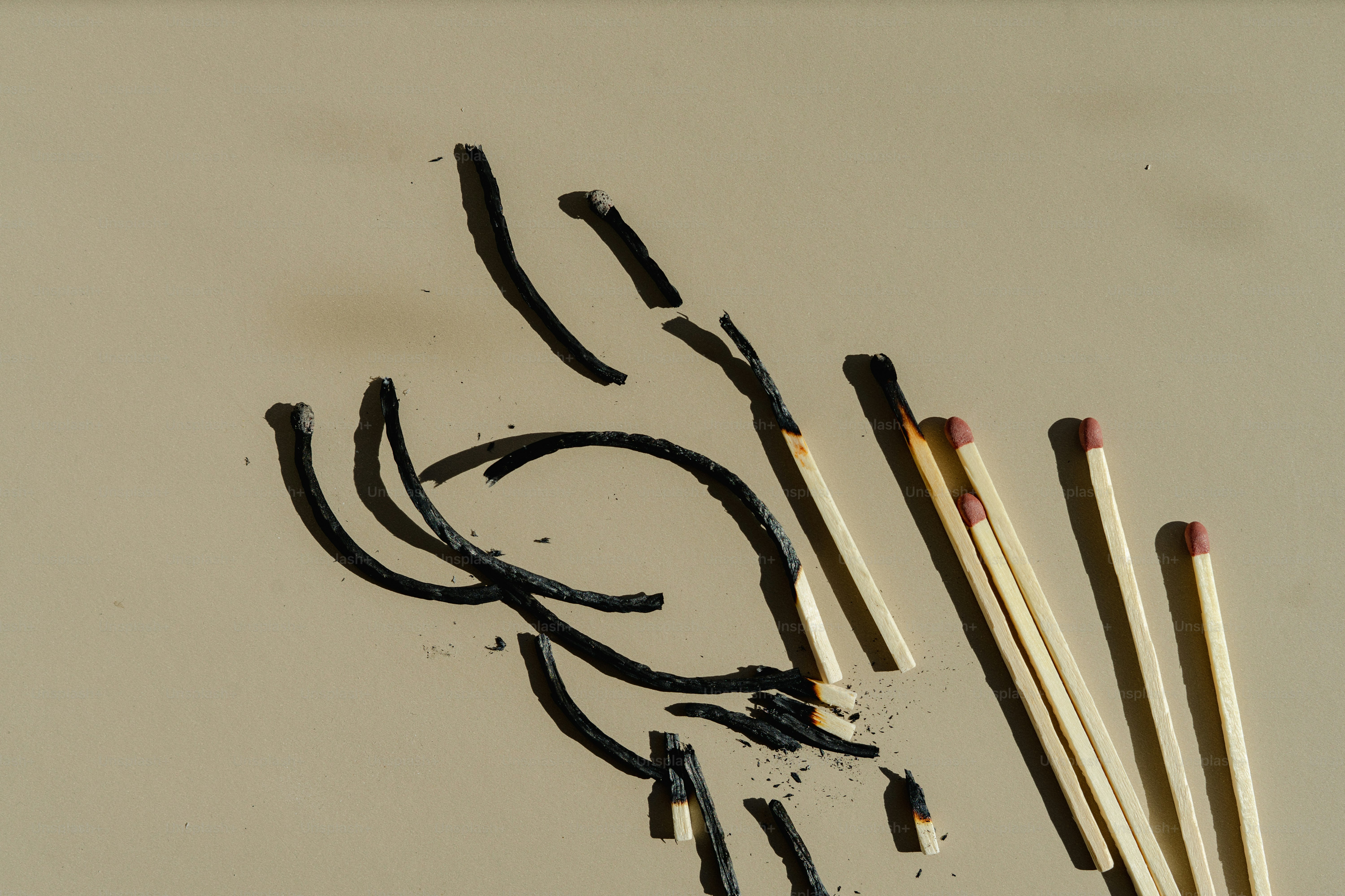 Burnt matches create a design on a light surface.