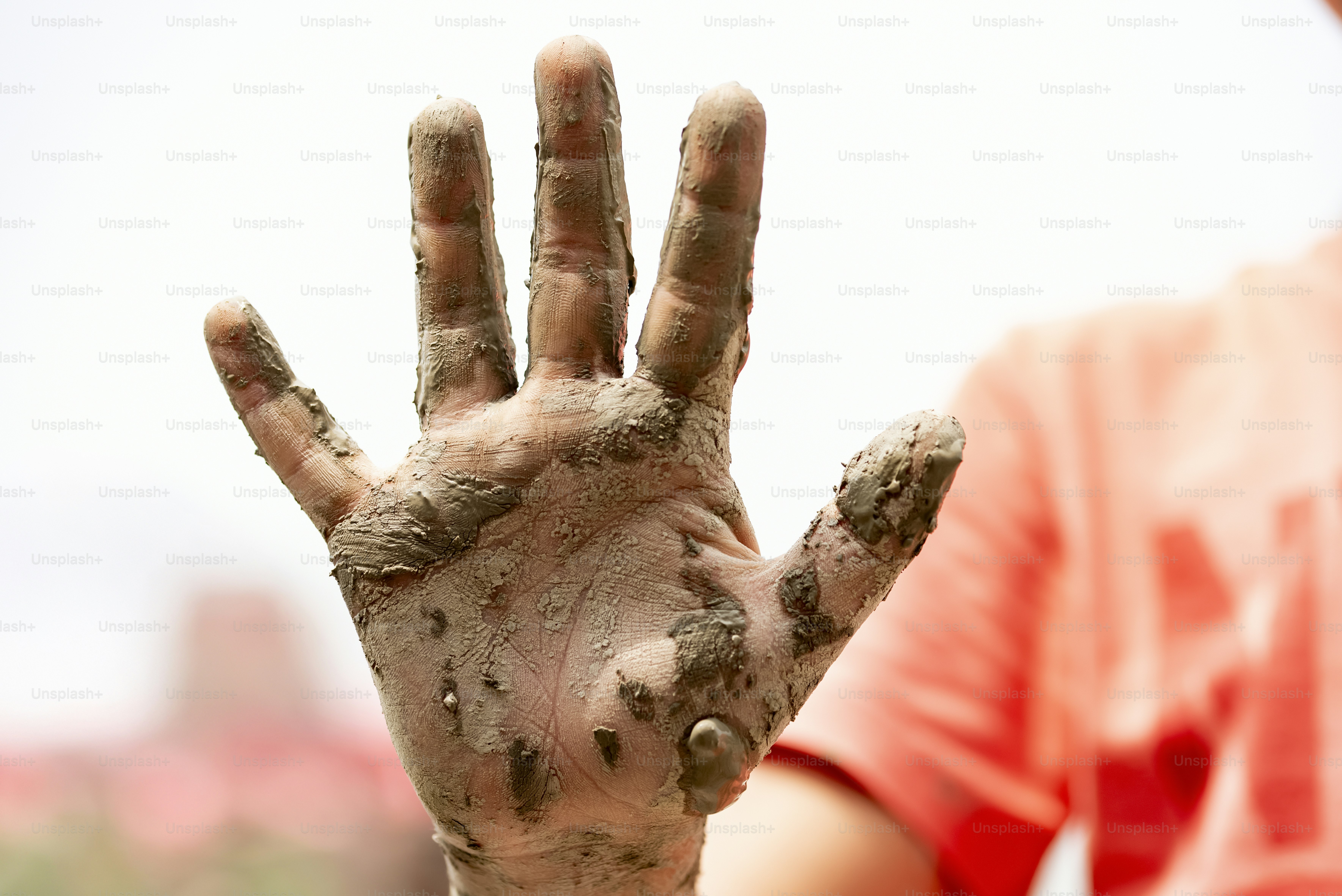 A muddy hand is showing four fingers.