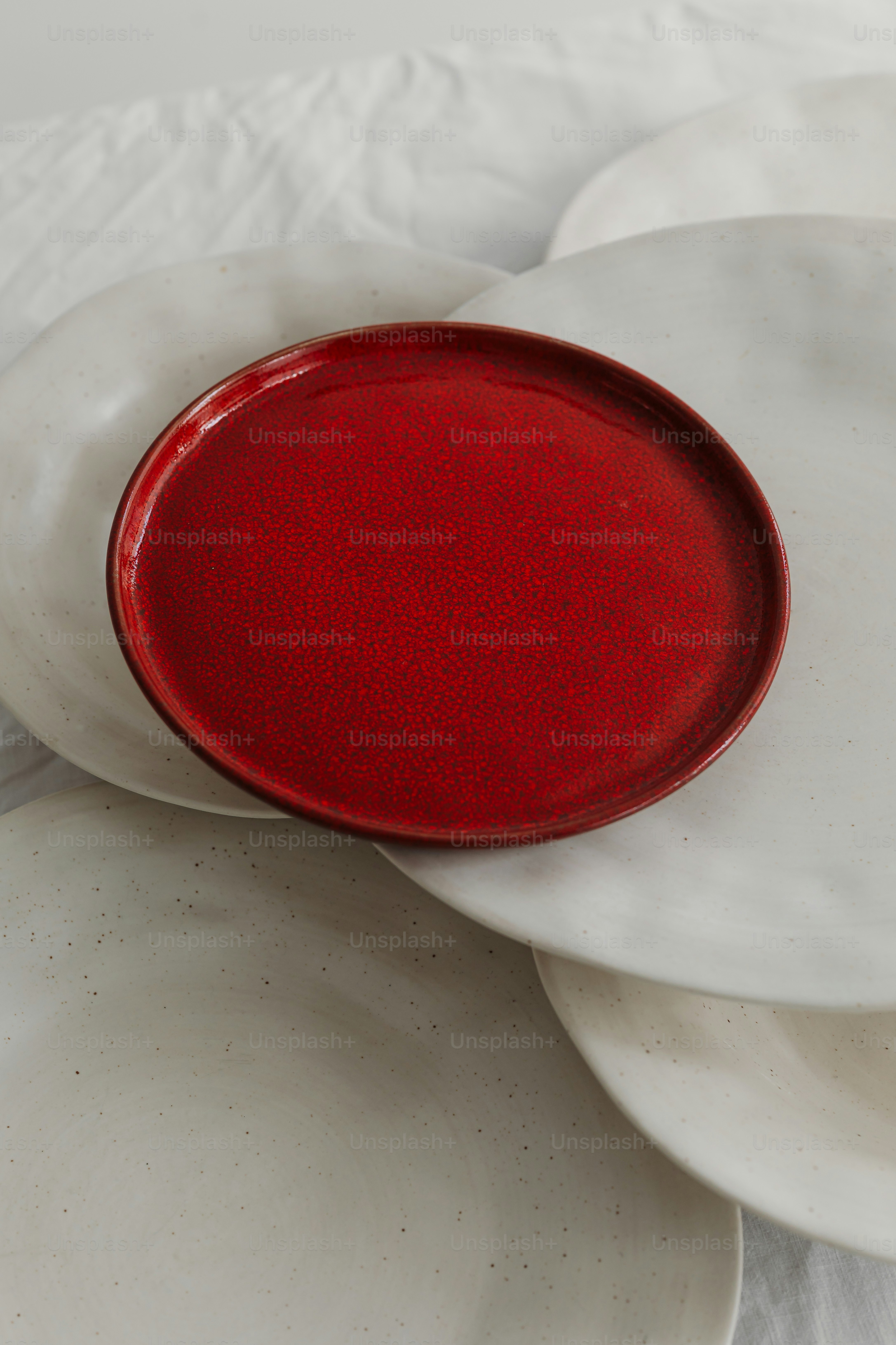 Assiette rouge sur assiettes blanches.
