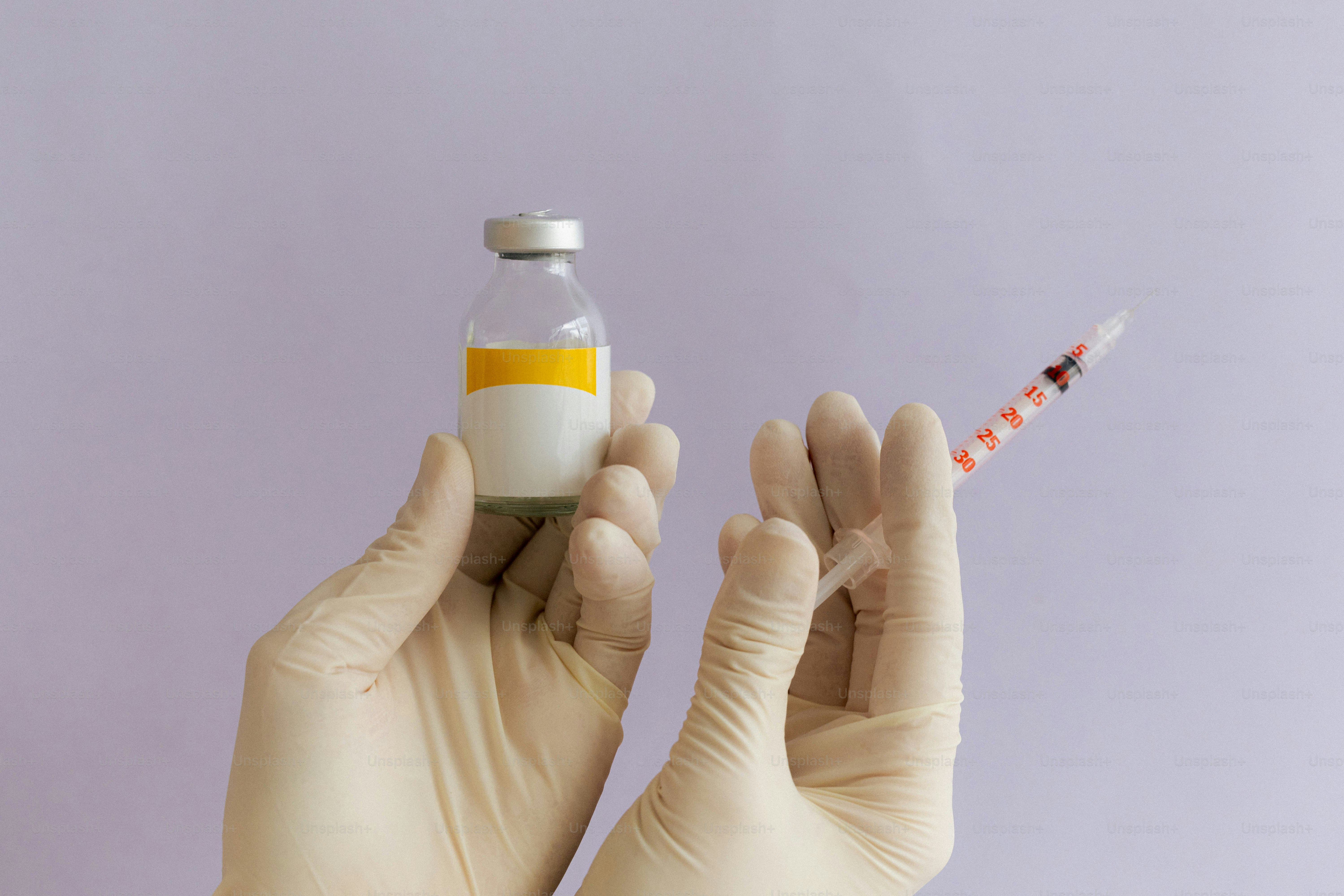 Hands hold a vial and a syringe.