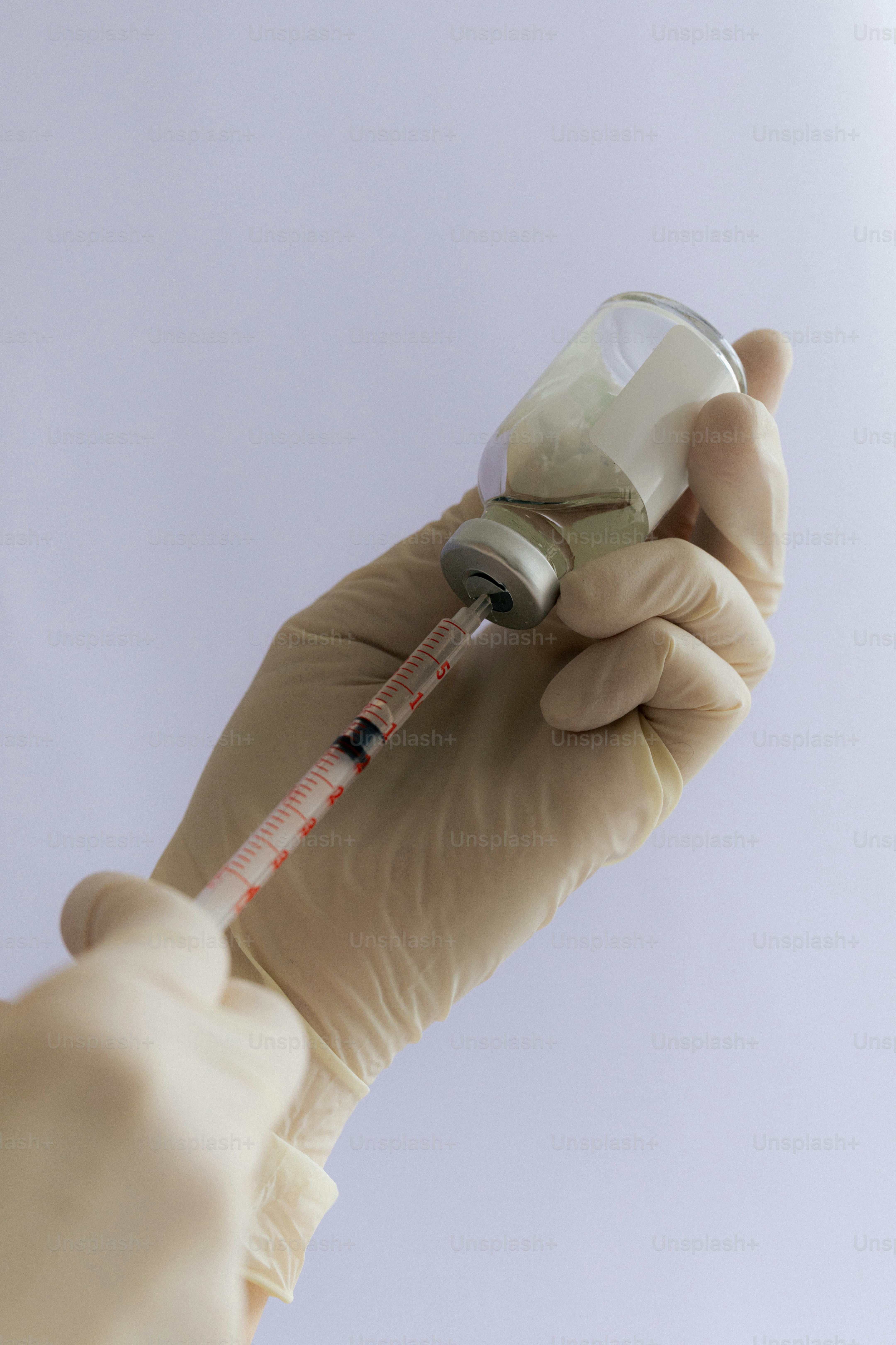 A syringe is drawing liquid from a vial.