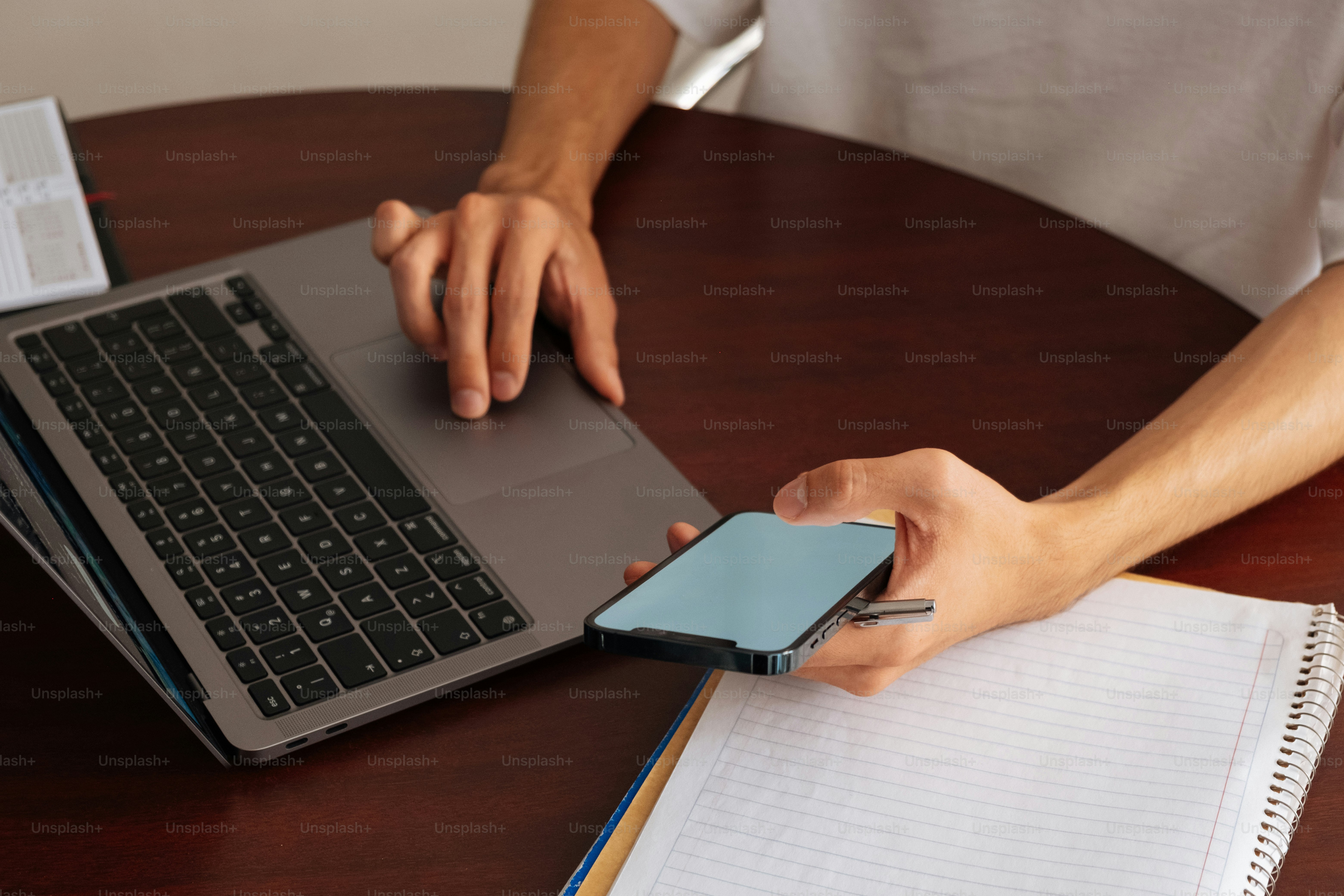 Orang yang menggunakan laptop dan ponsel secara bersamaan.