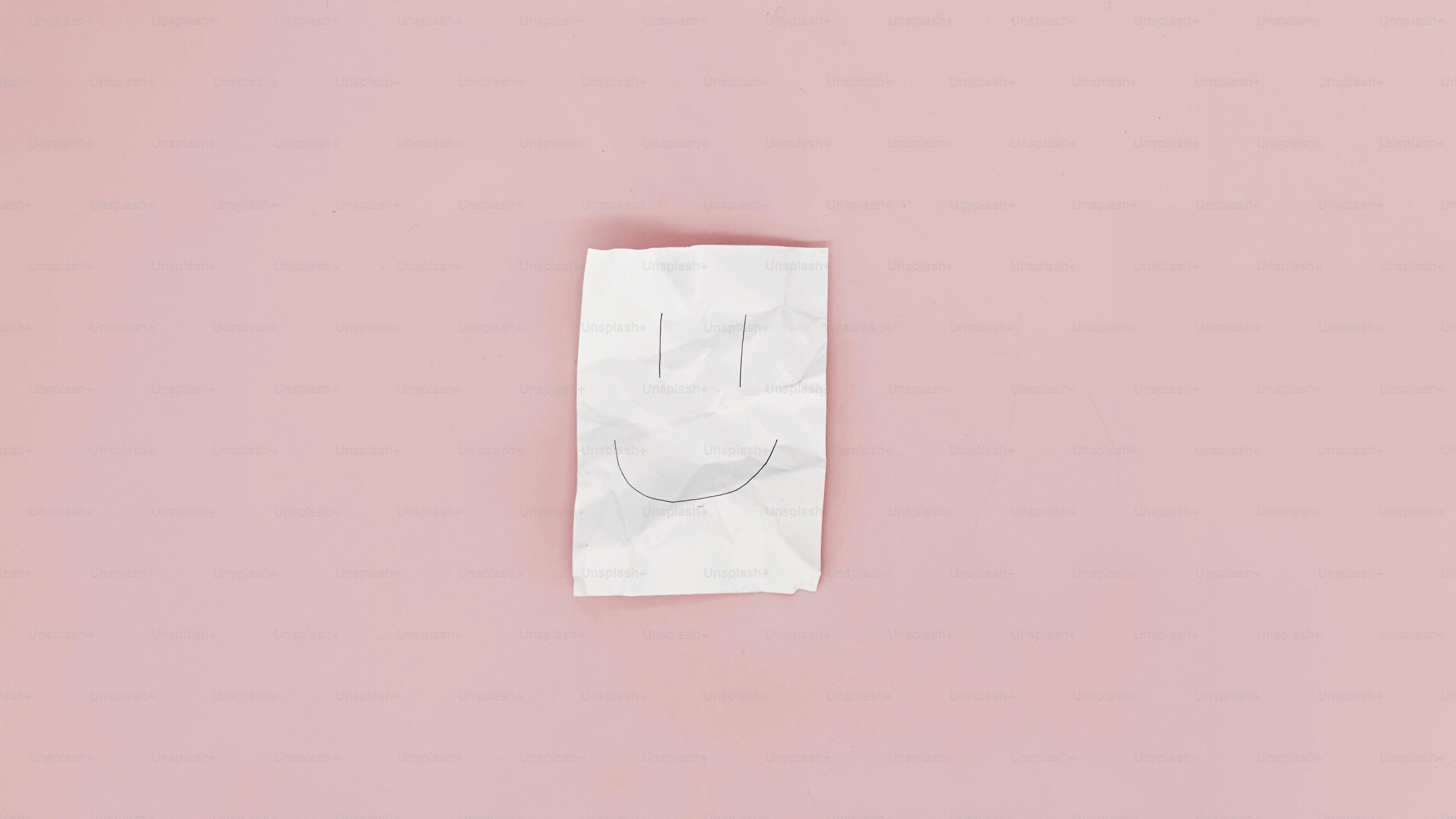 A crumpled paper bag rests on a pink surface.