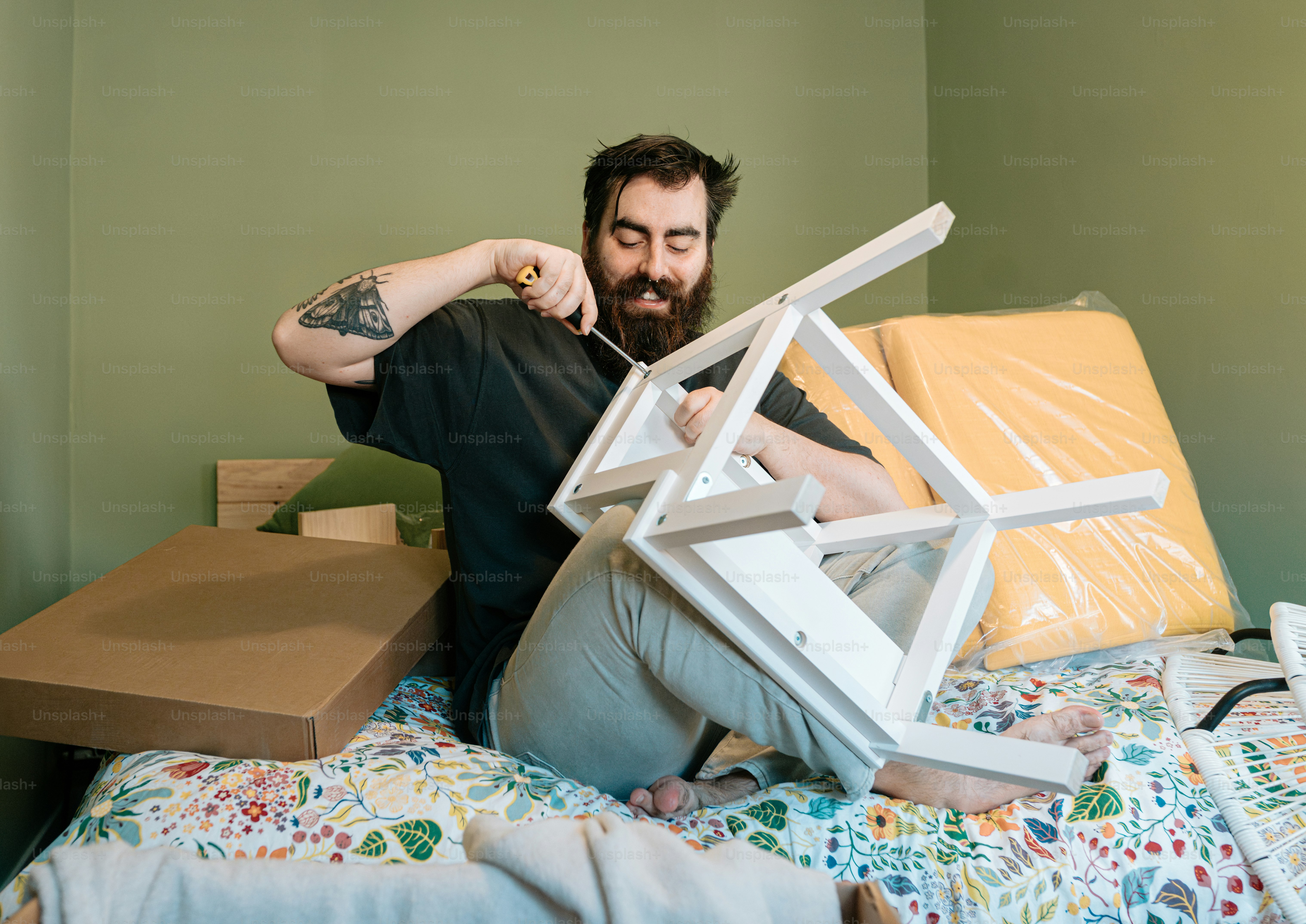 Man happily assembles furniture with a screwdriver.