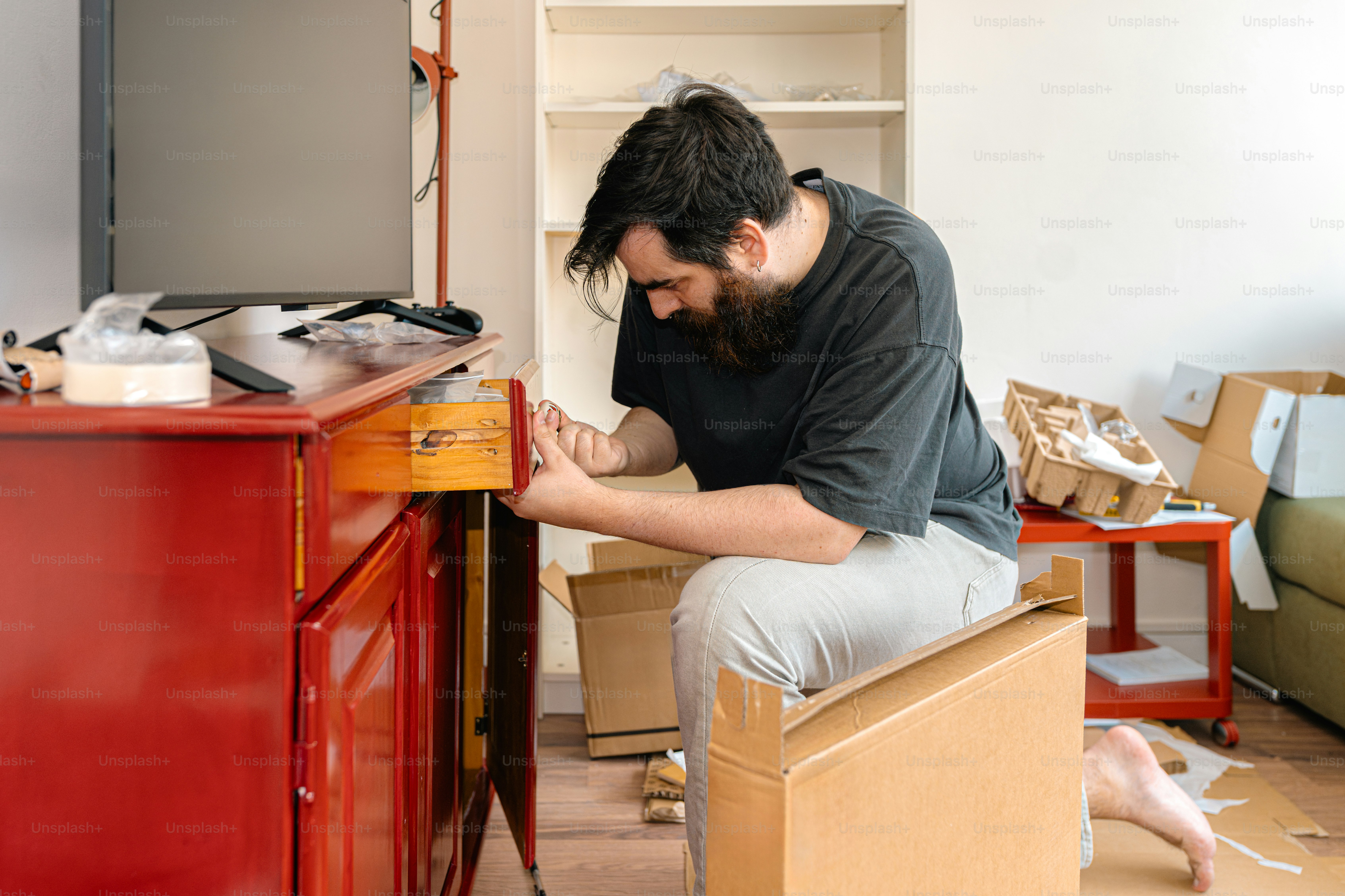 Man assembles furniture in a room.